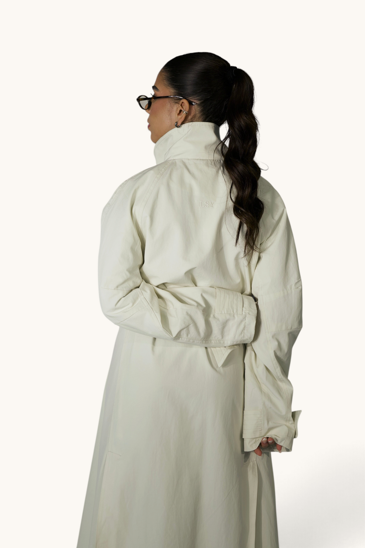 Langer Cream-Trenchcoat von LOSYANA, eleganter Mantel mit Gürtel und klassischen Revers, auf einem Kleiderbügel aufgehängt