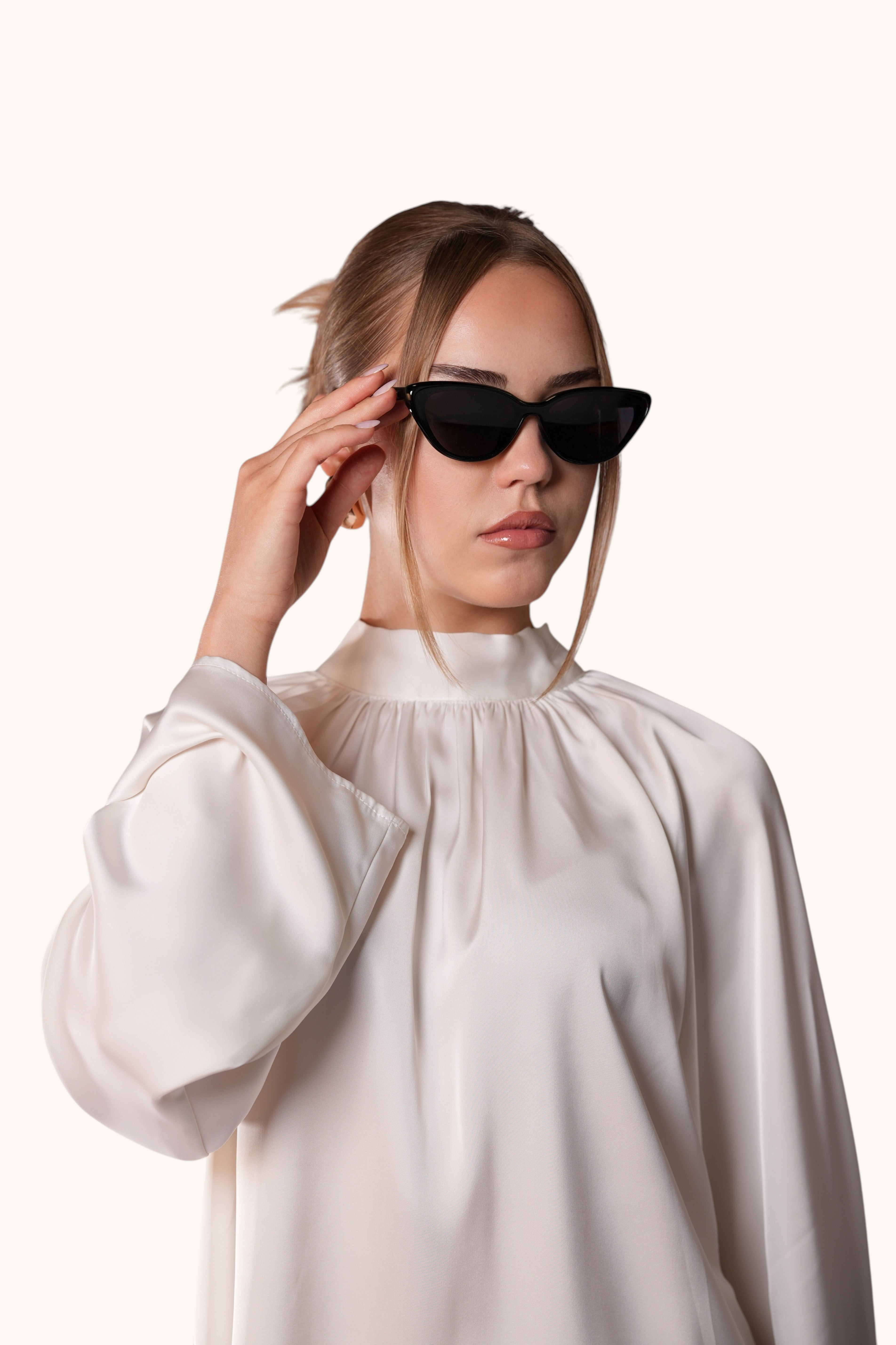 Woman wearing LOSYANA black cat-eye sunglasses with a white high-neck blouse against a white background