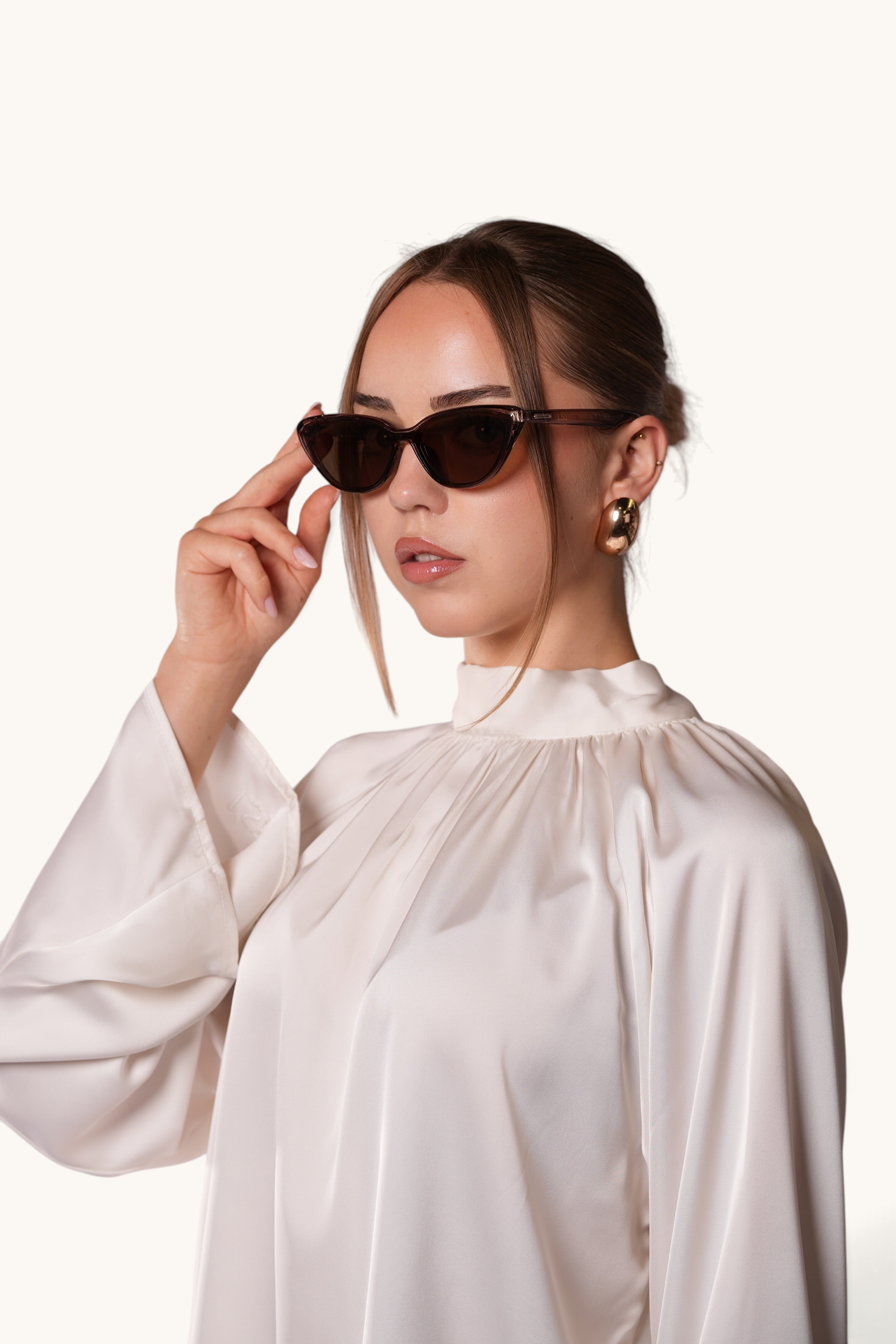 LOSYANA brown cat-eye sunglasses worn by a woman in a white satin blouse against a neutral background