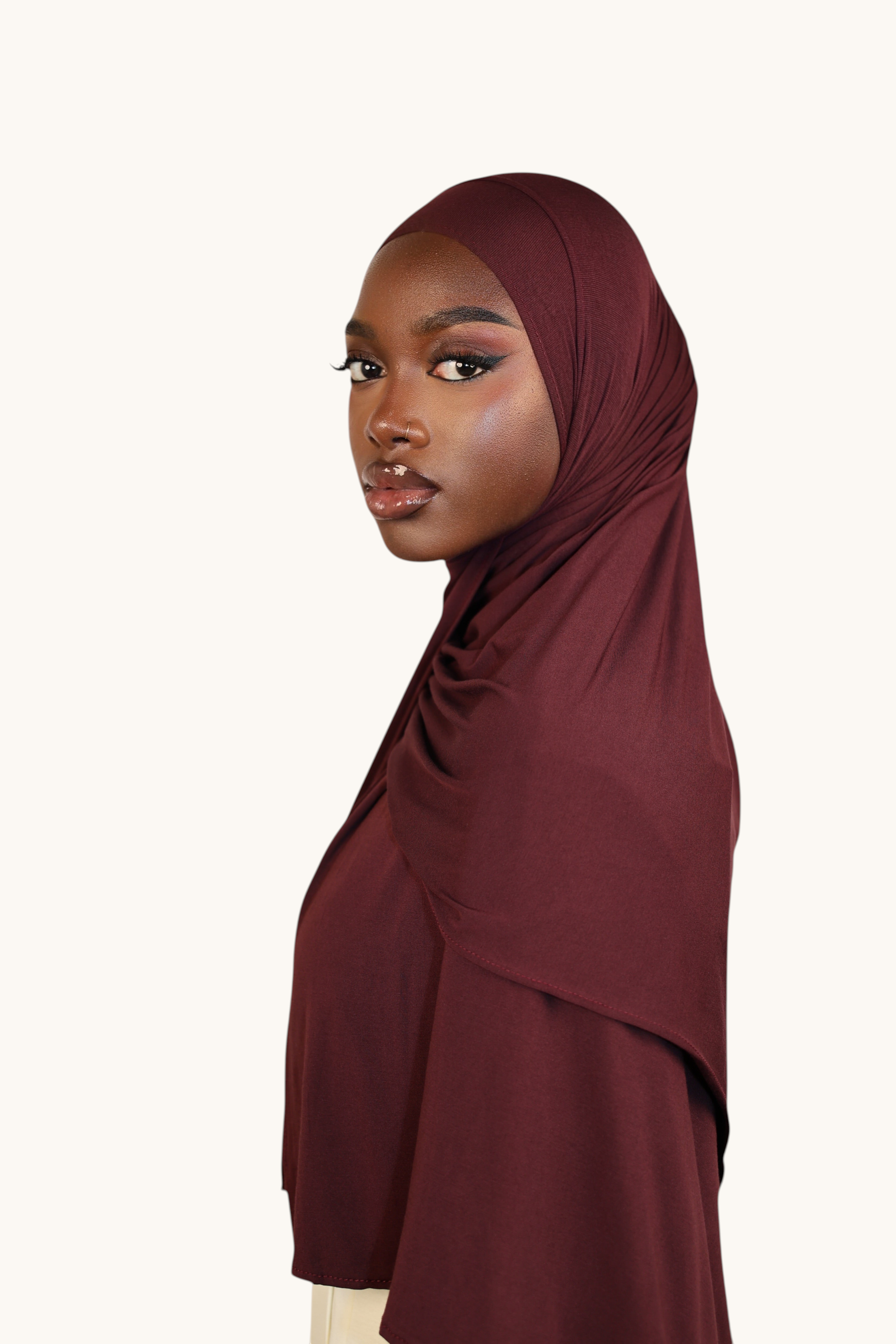 Model wearing a burgundy LOSYANA Vela Jersey hijab made of soft, breathable fabric, styled for an elegant look.