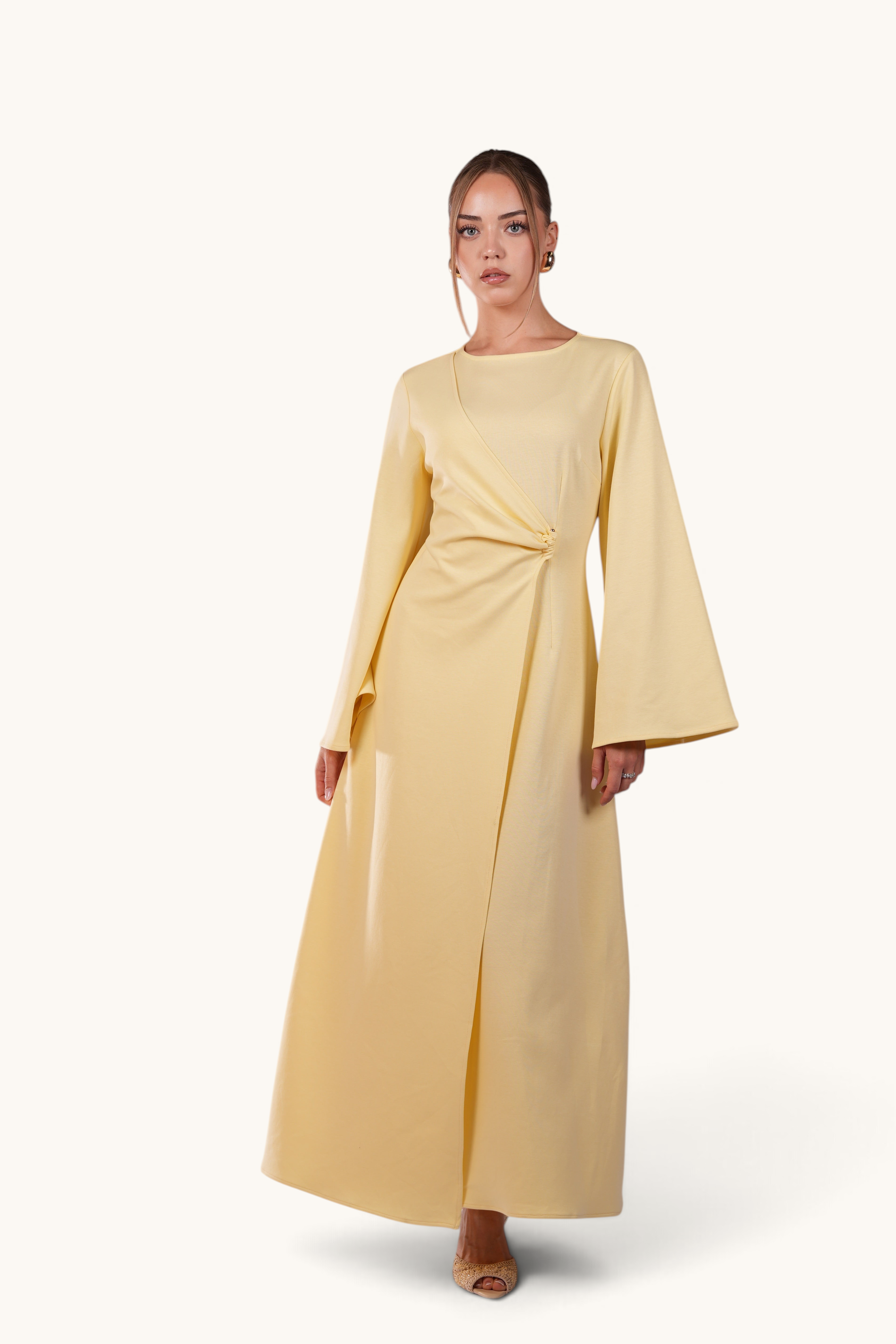 Model wearing LOSYANA butter yellow maxi dress with trumpet sleeves and gold waist detail against a white background