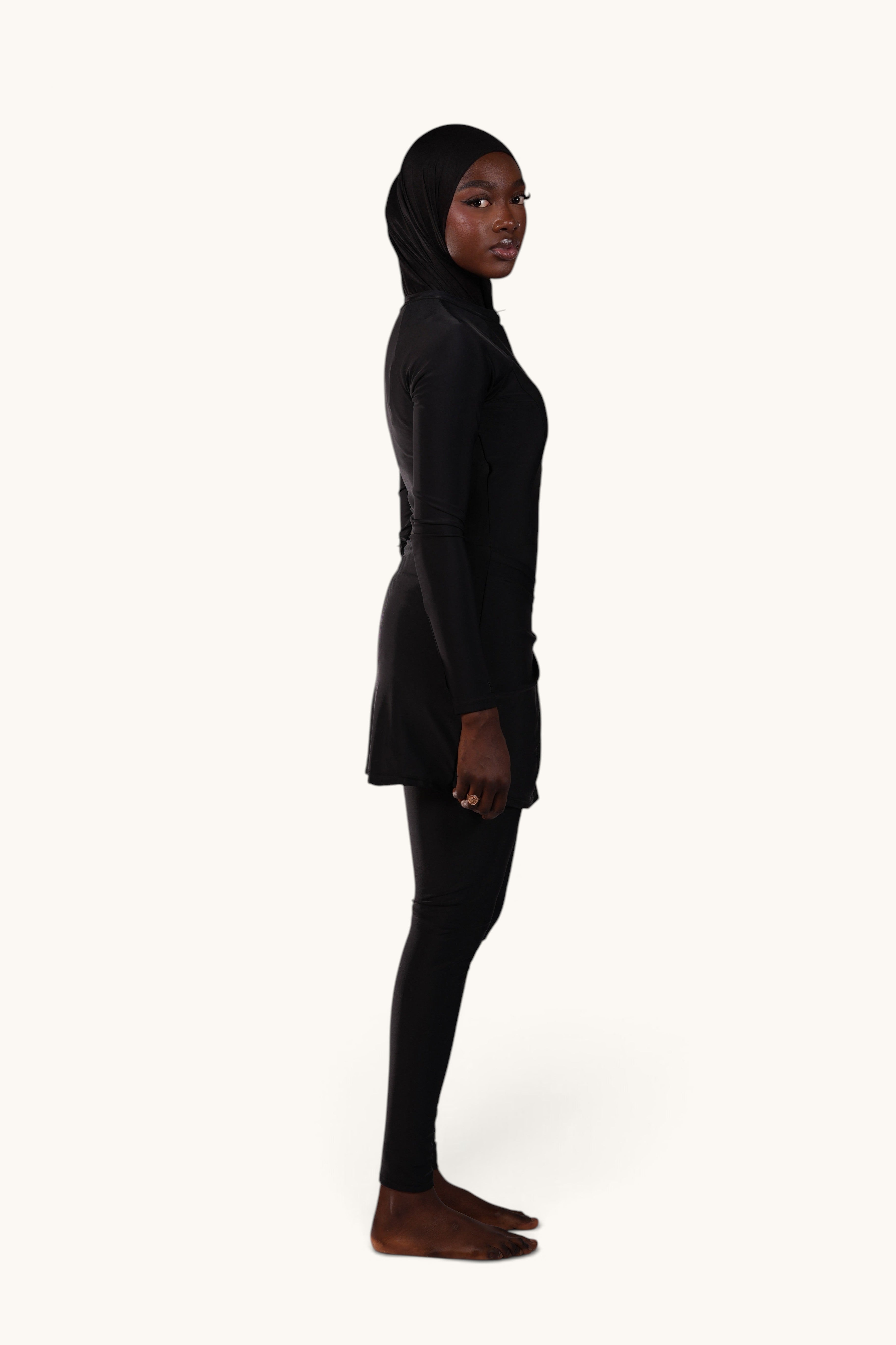 LOSYANA Costa Blanca black burkini with long sleeves, leggings, and matching swim cap, side view on a model.