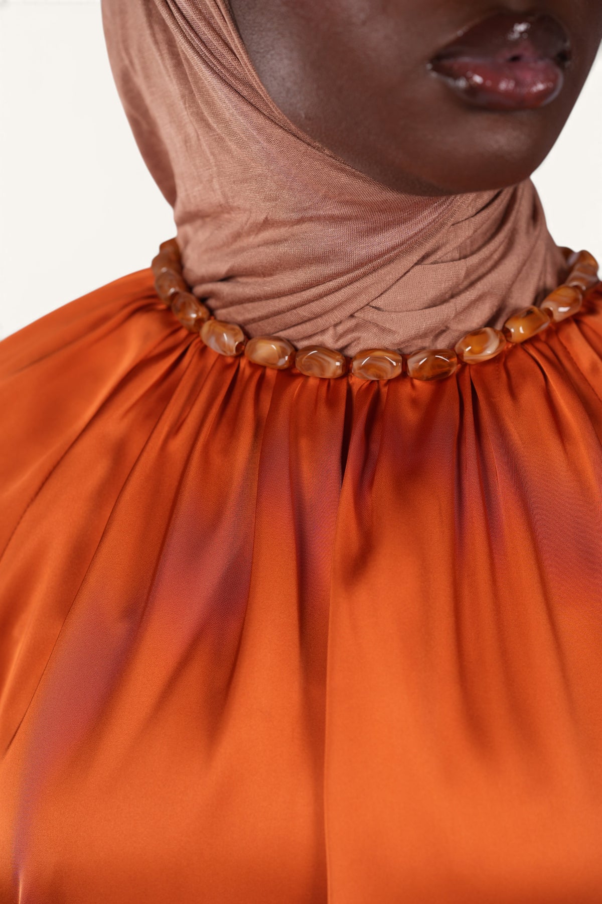 LOSYANA La Marina papaya satin top with a decorative acrylic stone collar worn by a model in a brown hijab