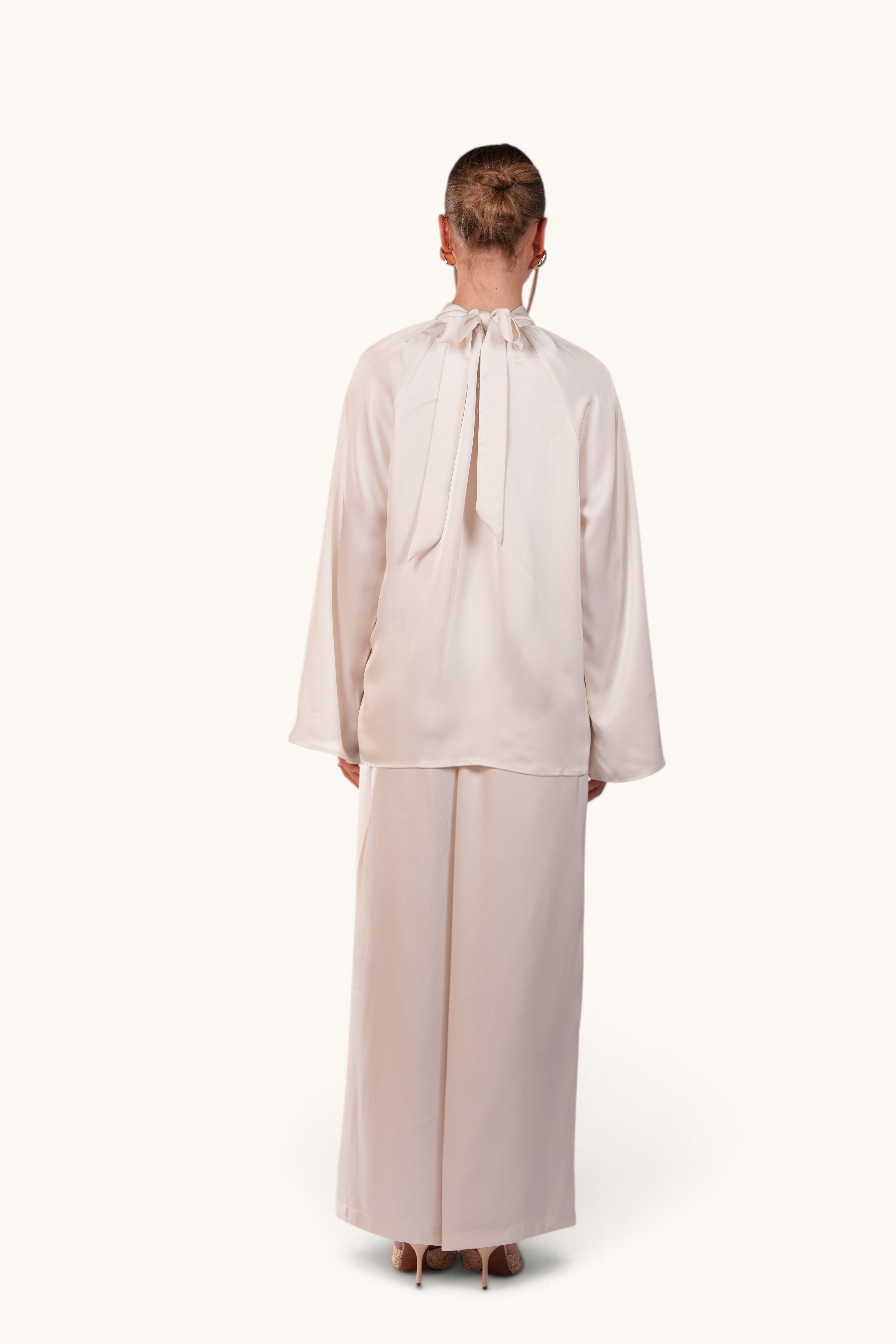 Back view of LOSYANA La Palma white satin two-piece set with high collar and bow tie detail on the back