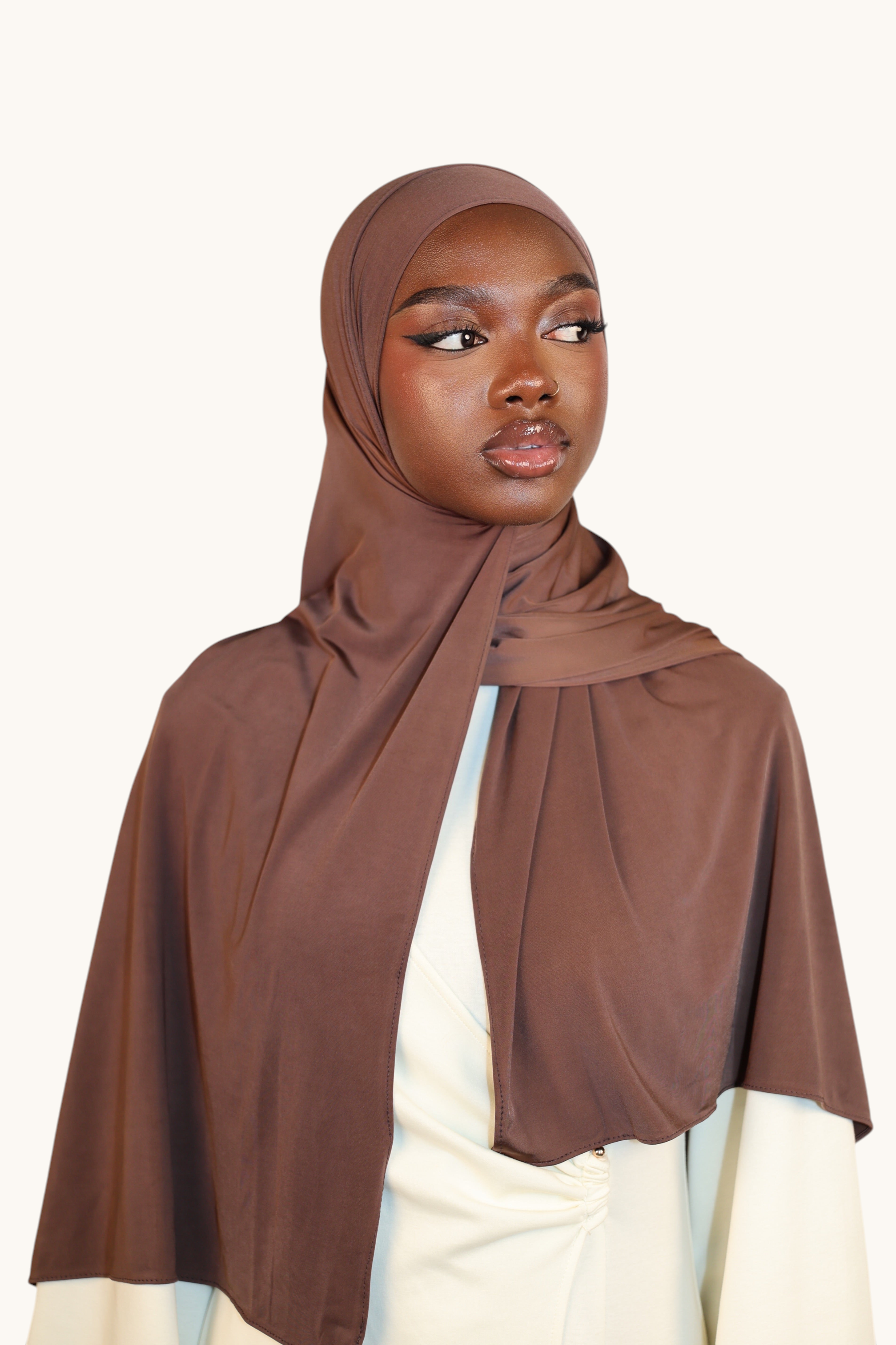 Model wearing a LOSYANA Liquid Jersey hijab in burnt sugar, a lightweight, slightly glossy brown headscarf.