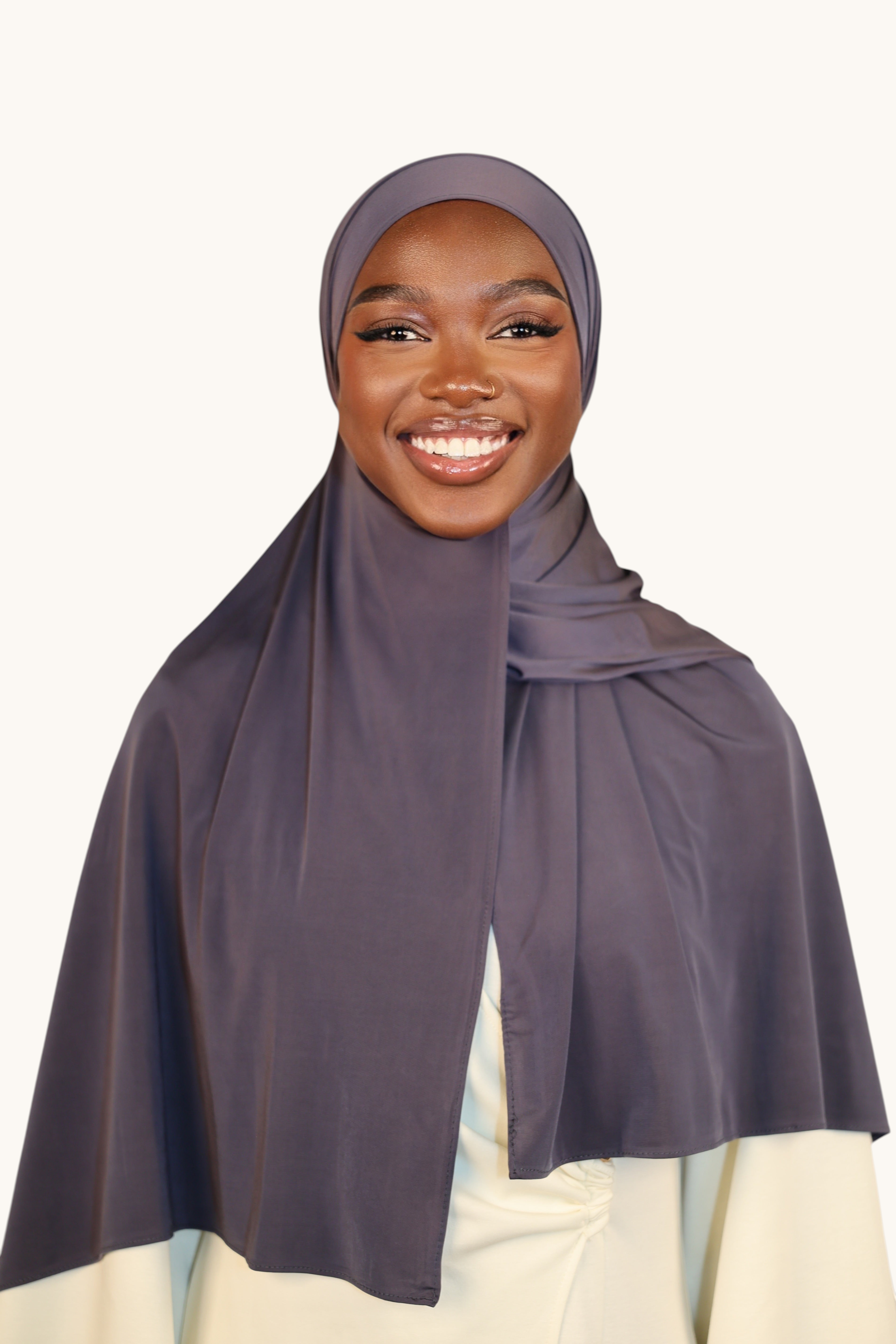 LOSYANA Liquid Jersey hijab in dusty blue worn by a smiling woman, featuring a lightweight, elegant satin finish.