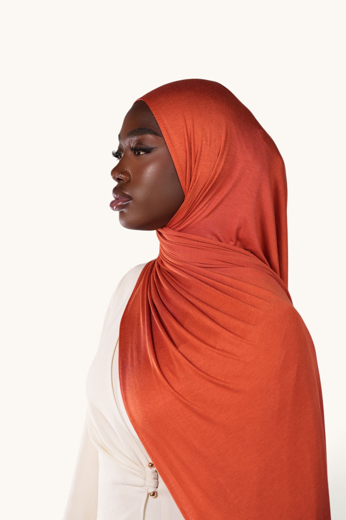 Model wearing a soft papaya orange LOSYANA bamboo jersey hijab, showcasing the lightweight and flowing fabric.
