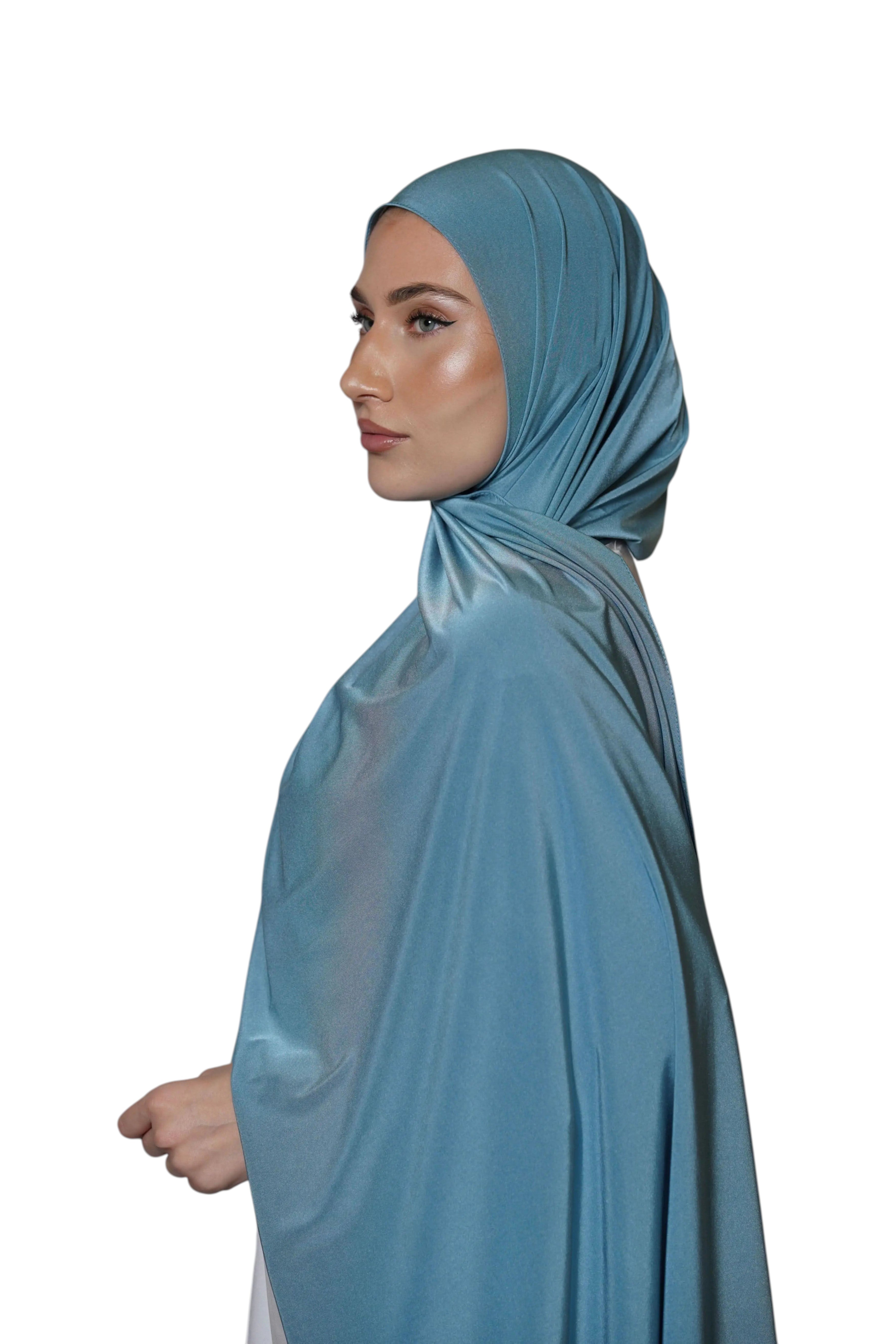 Model wearing a sky blue LOSYANA satin jersey hijab with a smooth, non-slip drape, side profile view.
