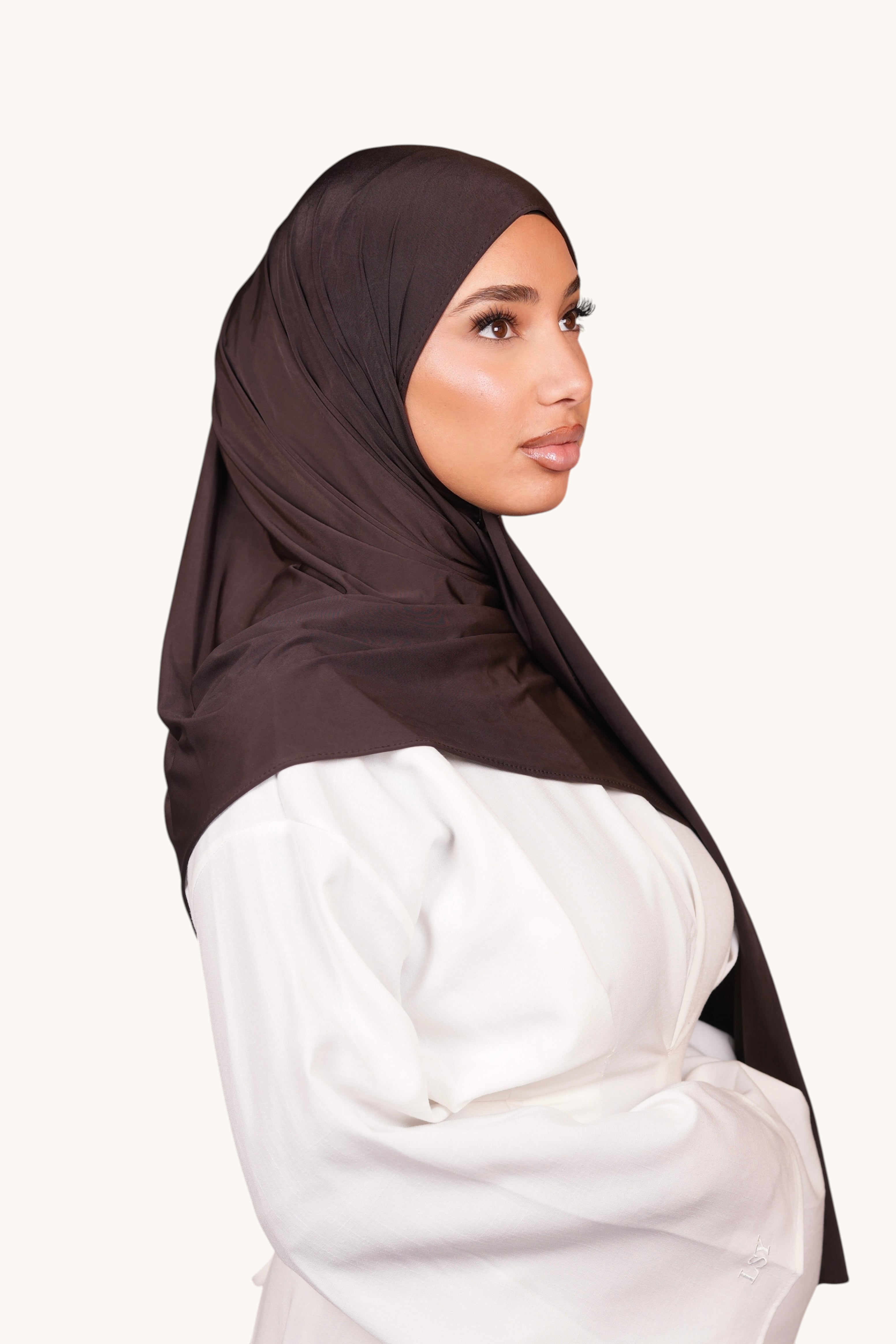 Model wearing a LOSYANA smokey chocolate liquid jersey hijab with a subtle satin sheen, side profile view.