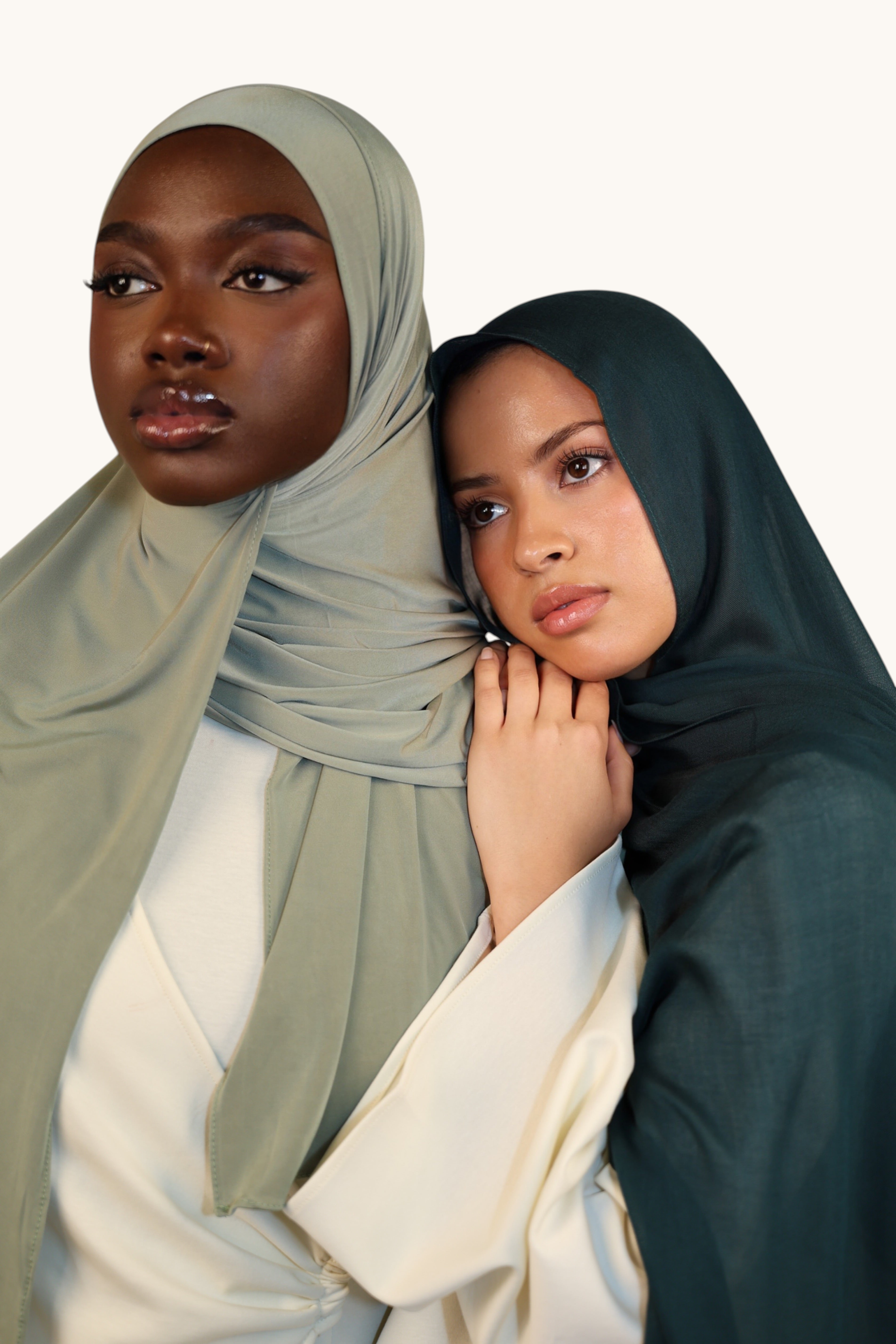 Two models wearing LOSYANA lightweight teal green and sage modal hijabs with a soft, elegant draped finish.