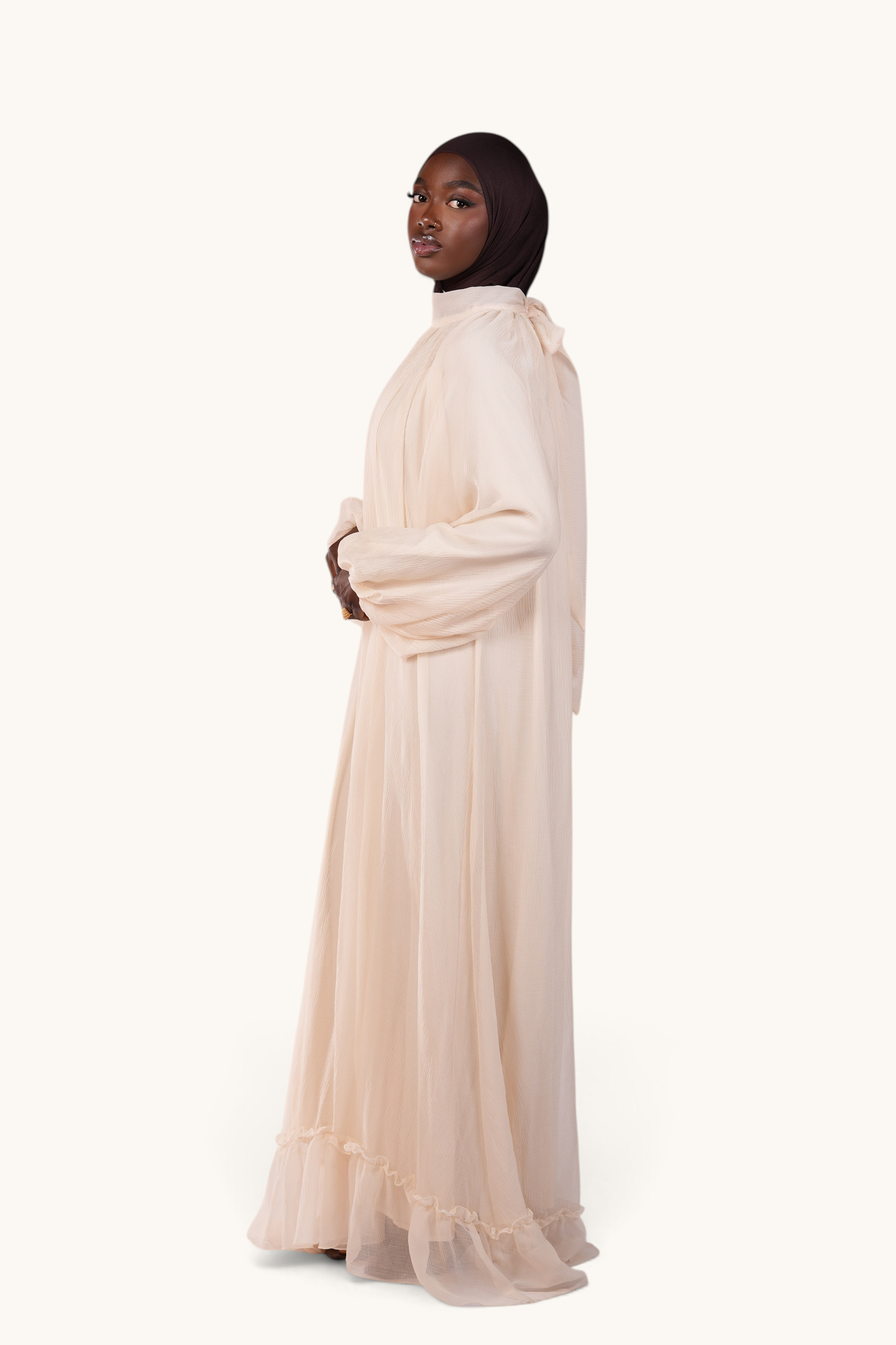 LOSYANA Tenerife ivory crepe maxi dress with balloon sleeves, high collar, and back bow detail on a model.