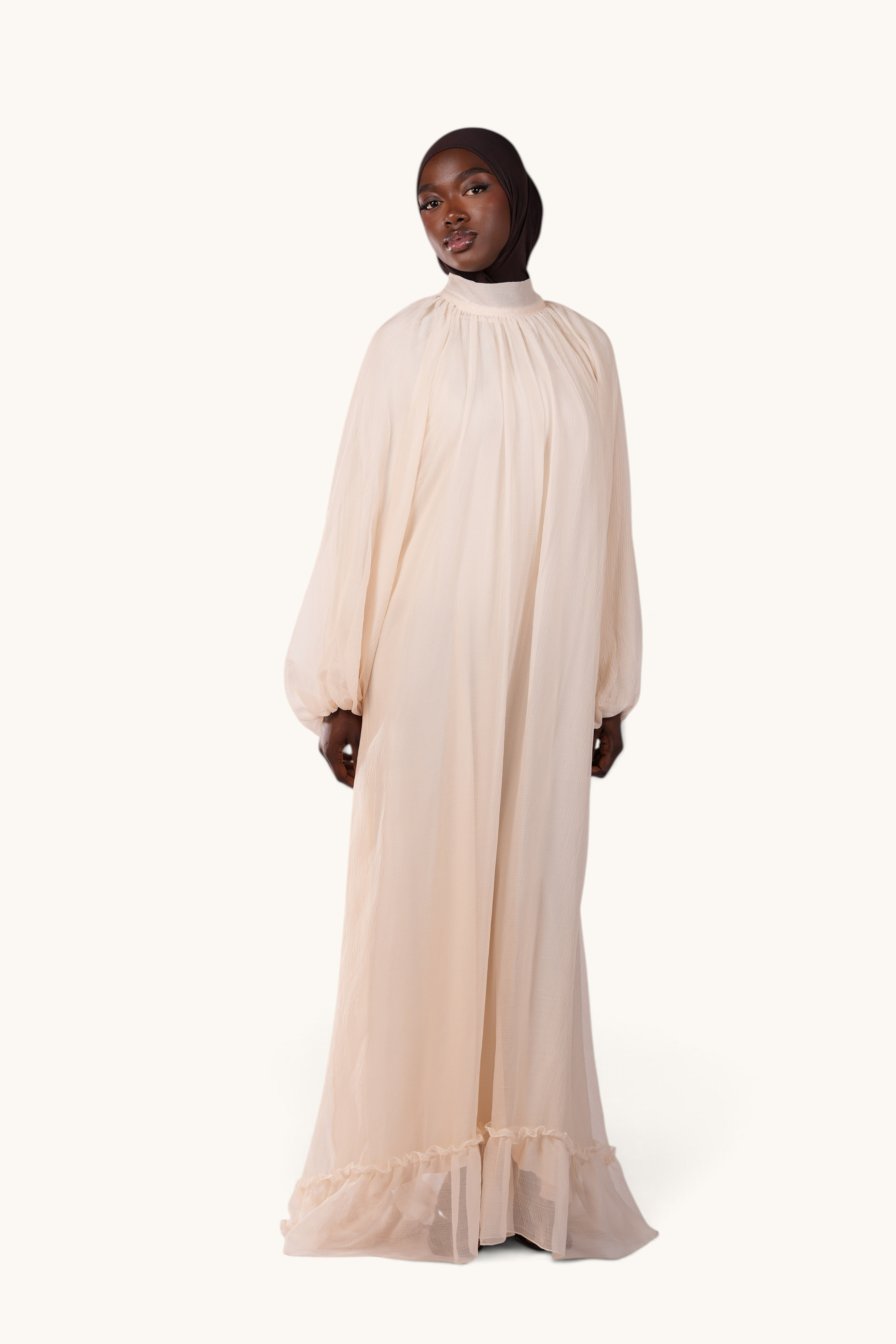 LOSYANA Tenerife ivory crepe maxi dress with high neck, balloon sleeves, and ruffled hem on a model