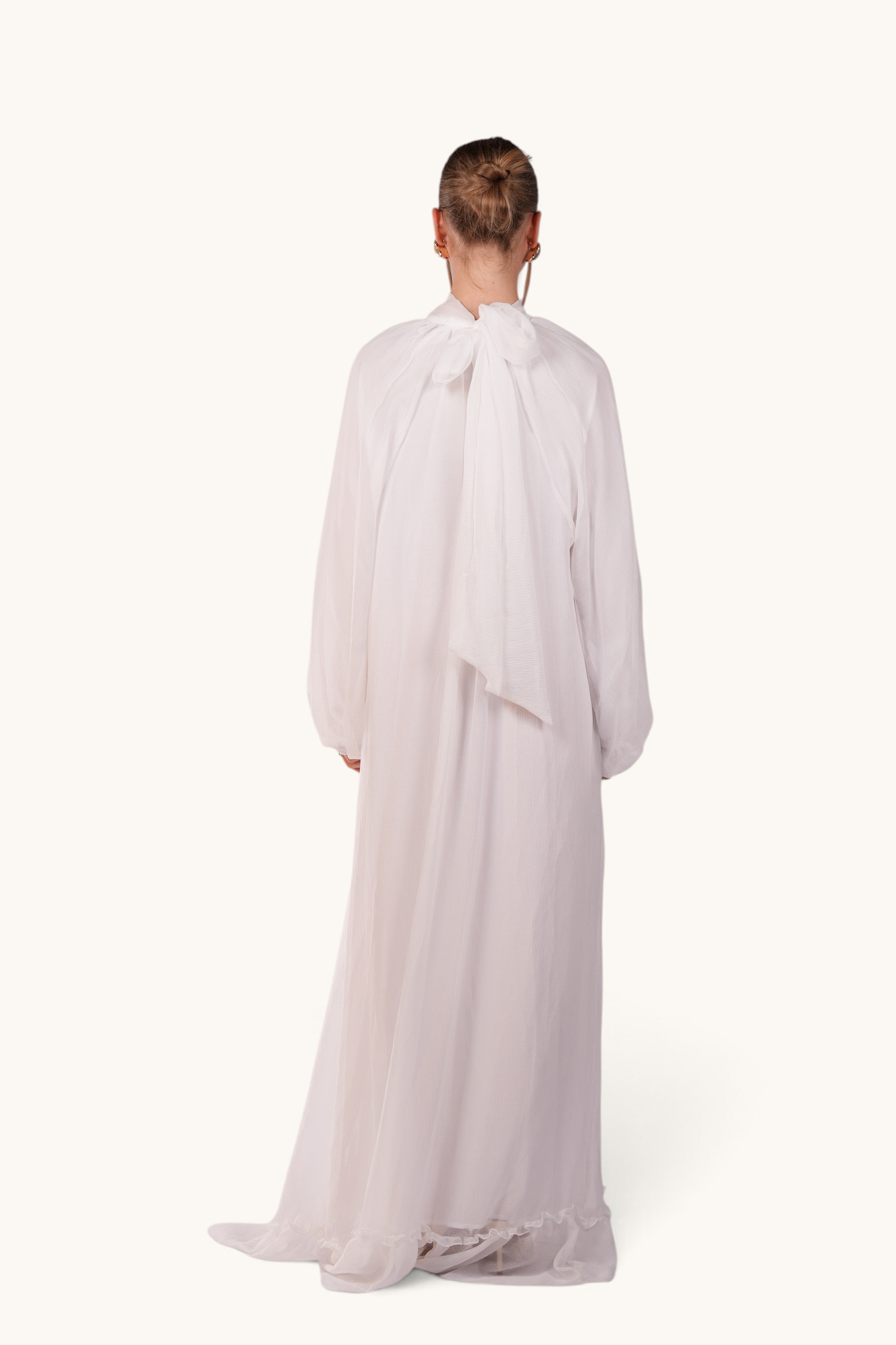 LOSYANA Tenerife white crepe maxi dress with balloon sleeves and back bow detail worn by a model, back view