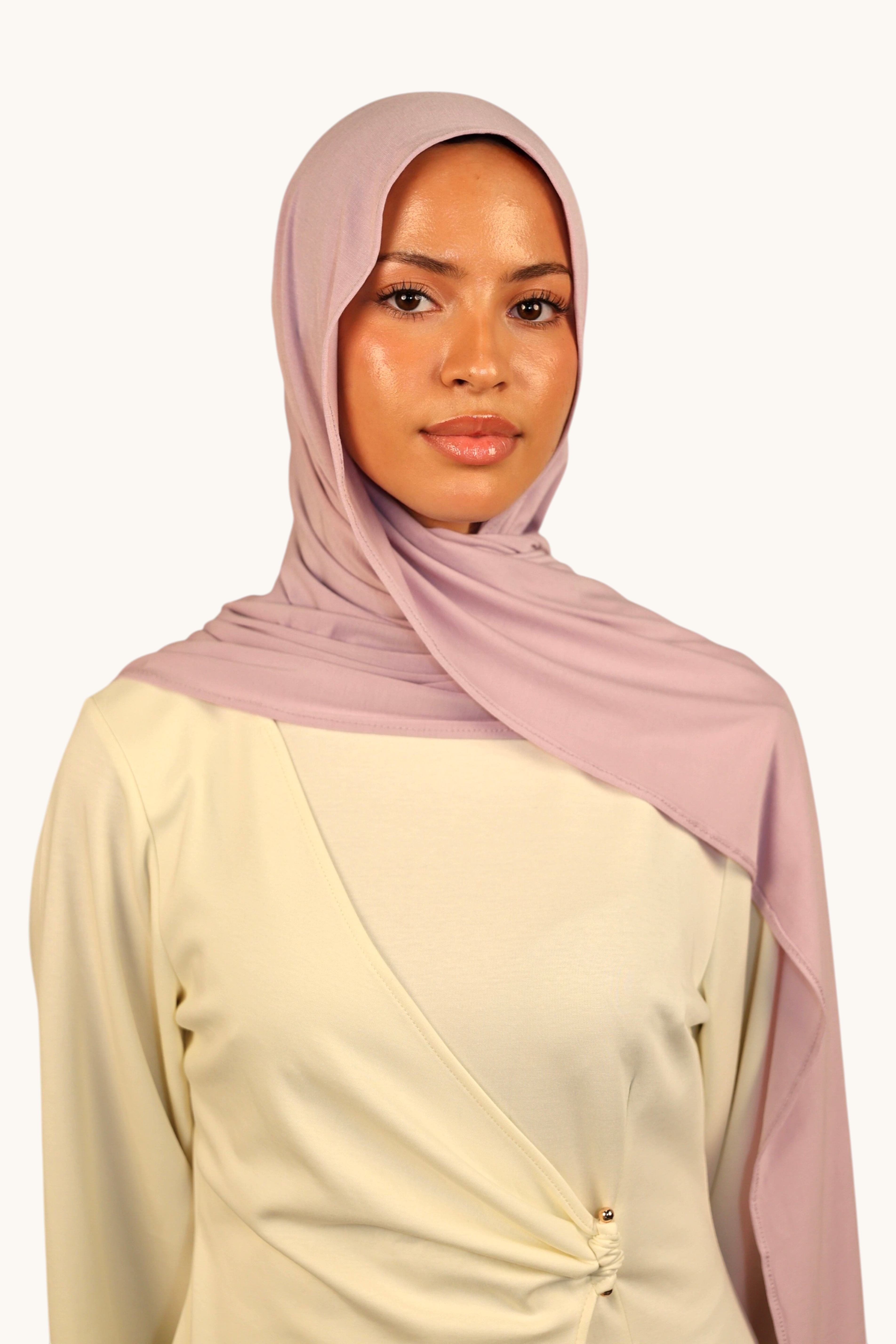 Model wearing a soft lavender LOSYANA Vela Jersey hijab, styled elegantly over a cream-colored wrap top.