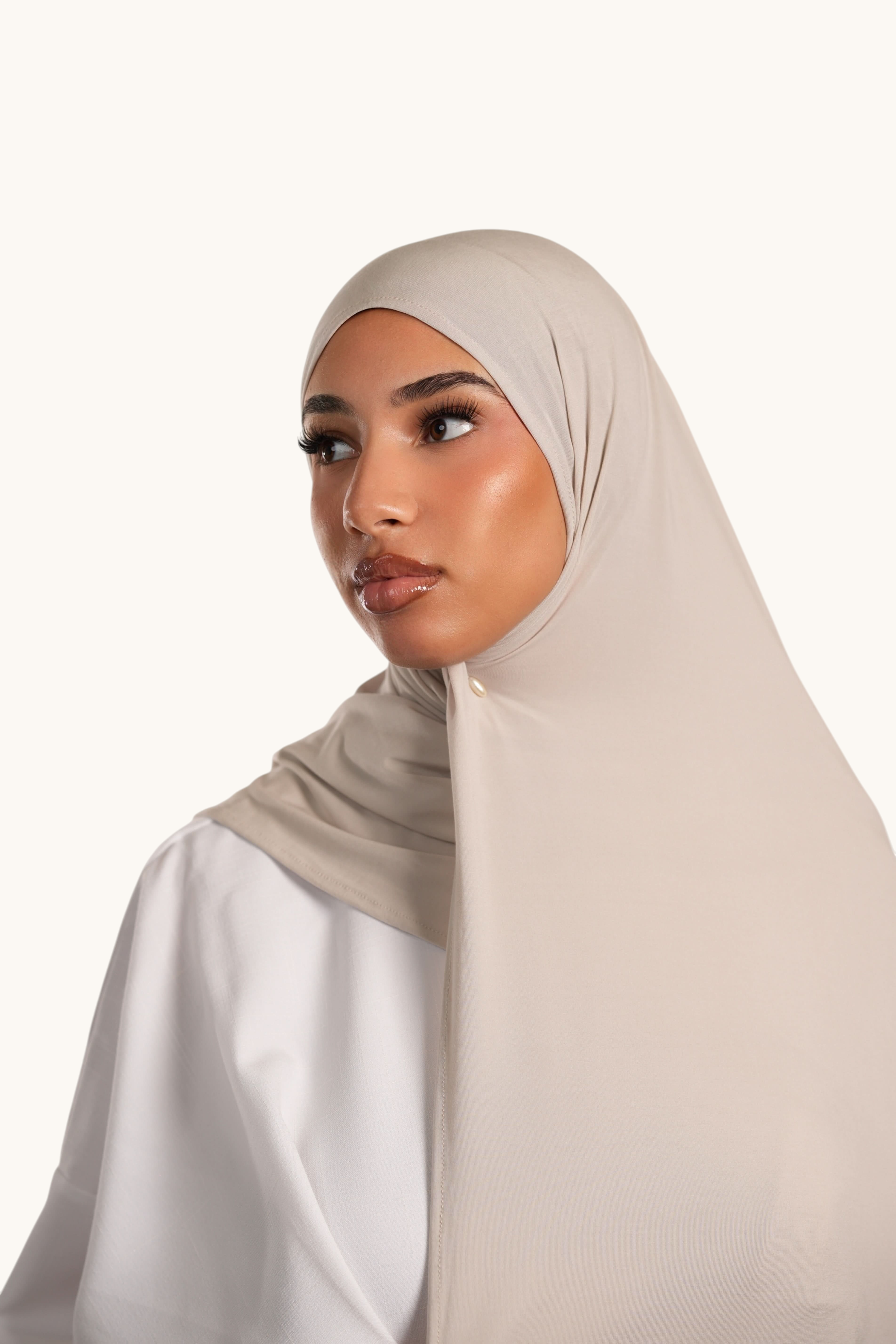 Model wearing a light beige LOSYANA Vela Jersey hijab, crafted from soft, breathable fabric for elegant styling.