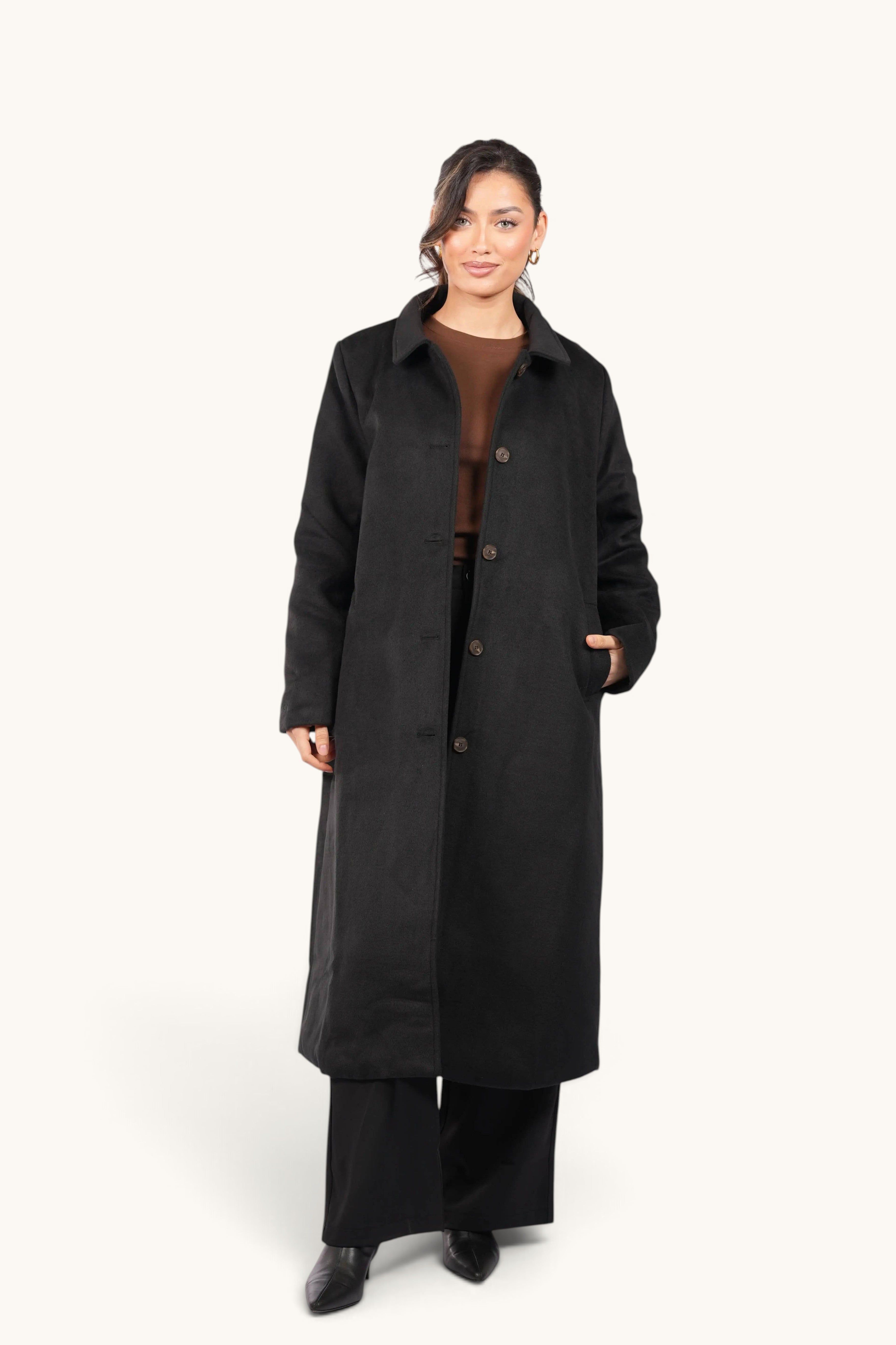 Model wearing a LOSYANA black Vienna coat with a classic collar and button-down front in a studio setting