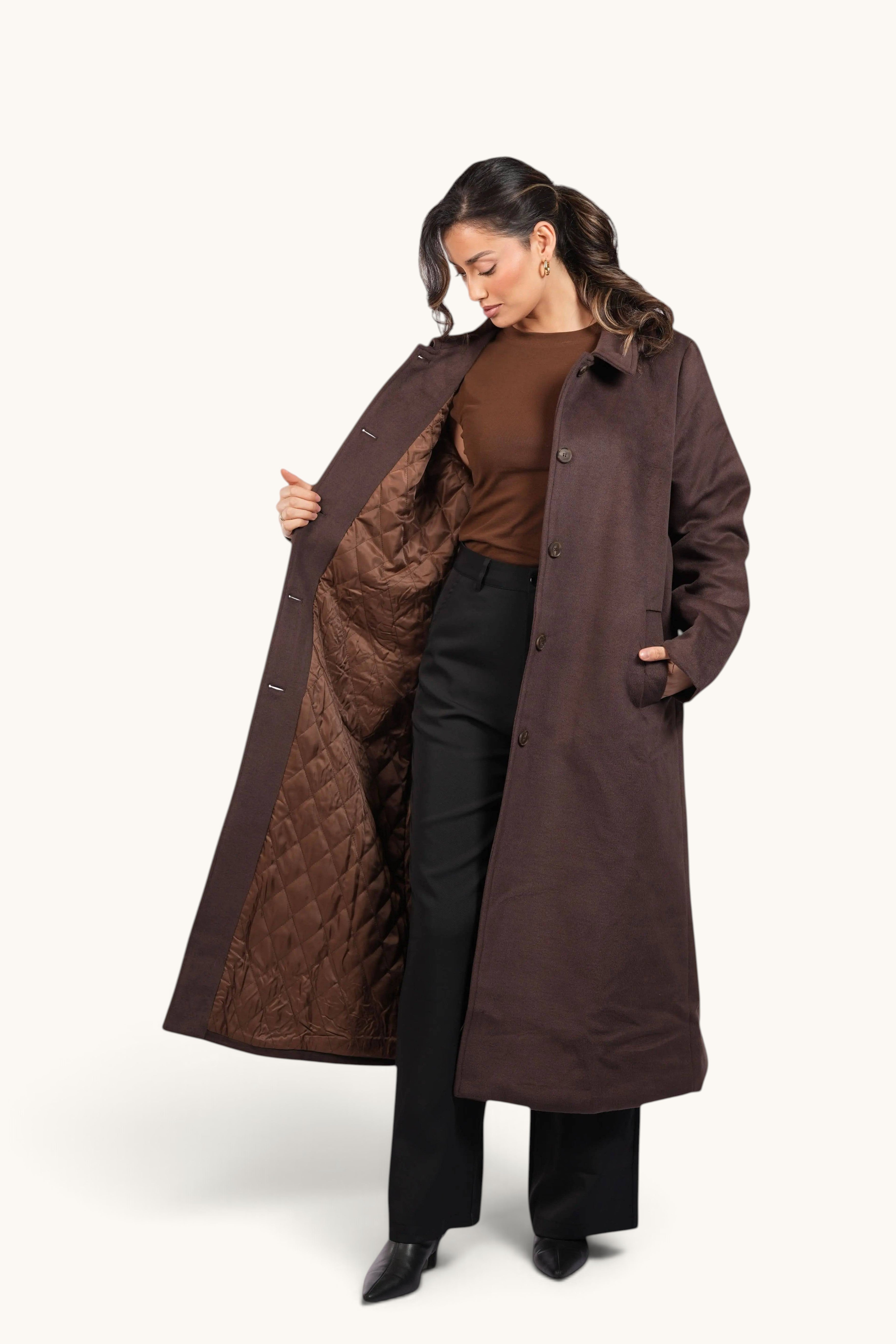 Model wearing a long, espresso brown LOSYANA Vienna coat with a quilted lining, open to show the interior detail.