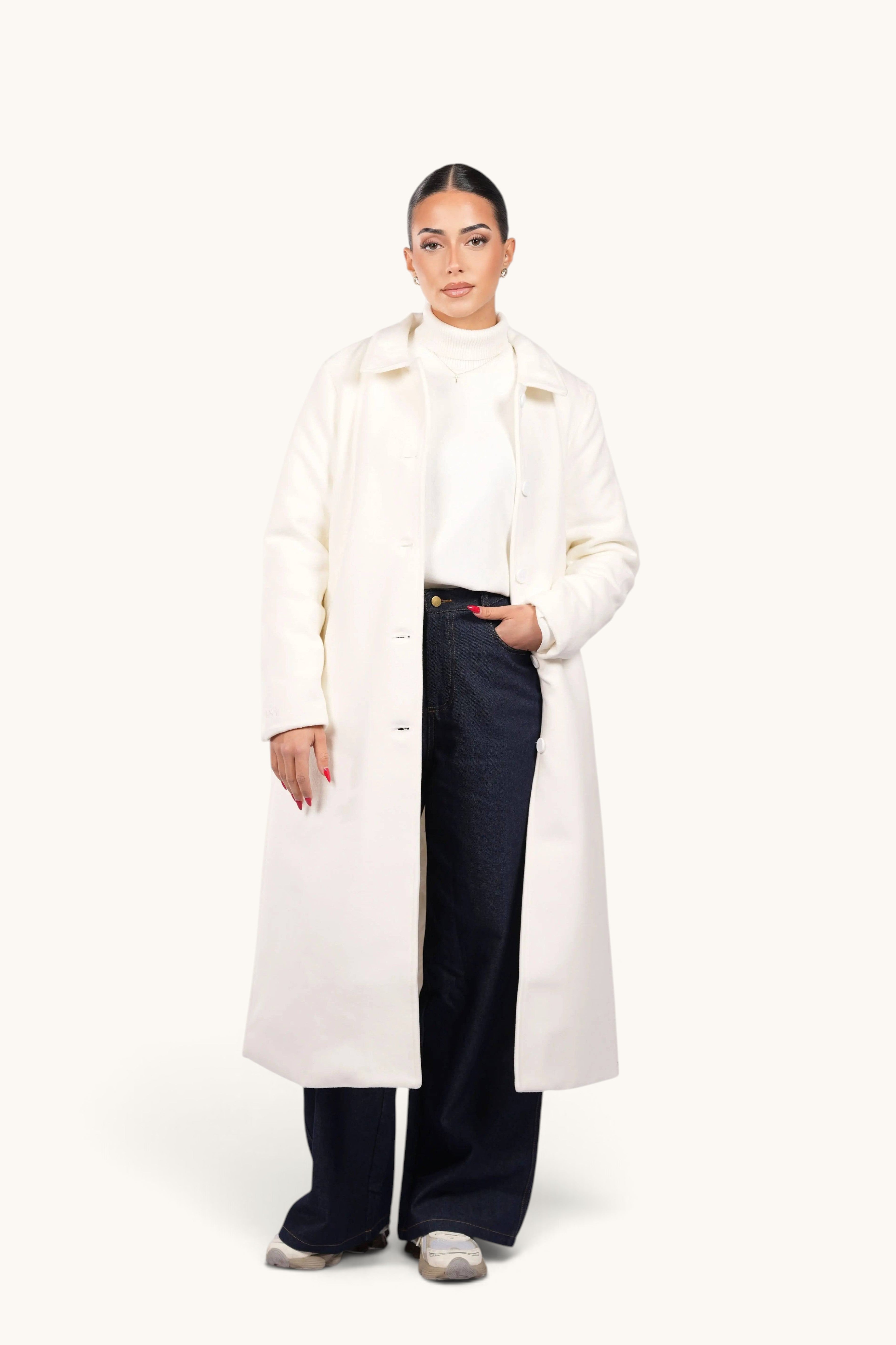 LOSYANA The Vienna Coat in white worn by a model with dark jeans and a white turtleneck sweater