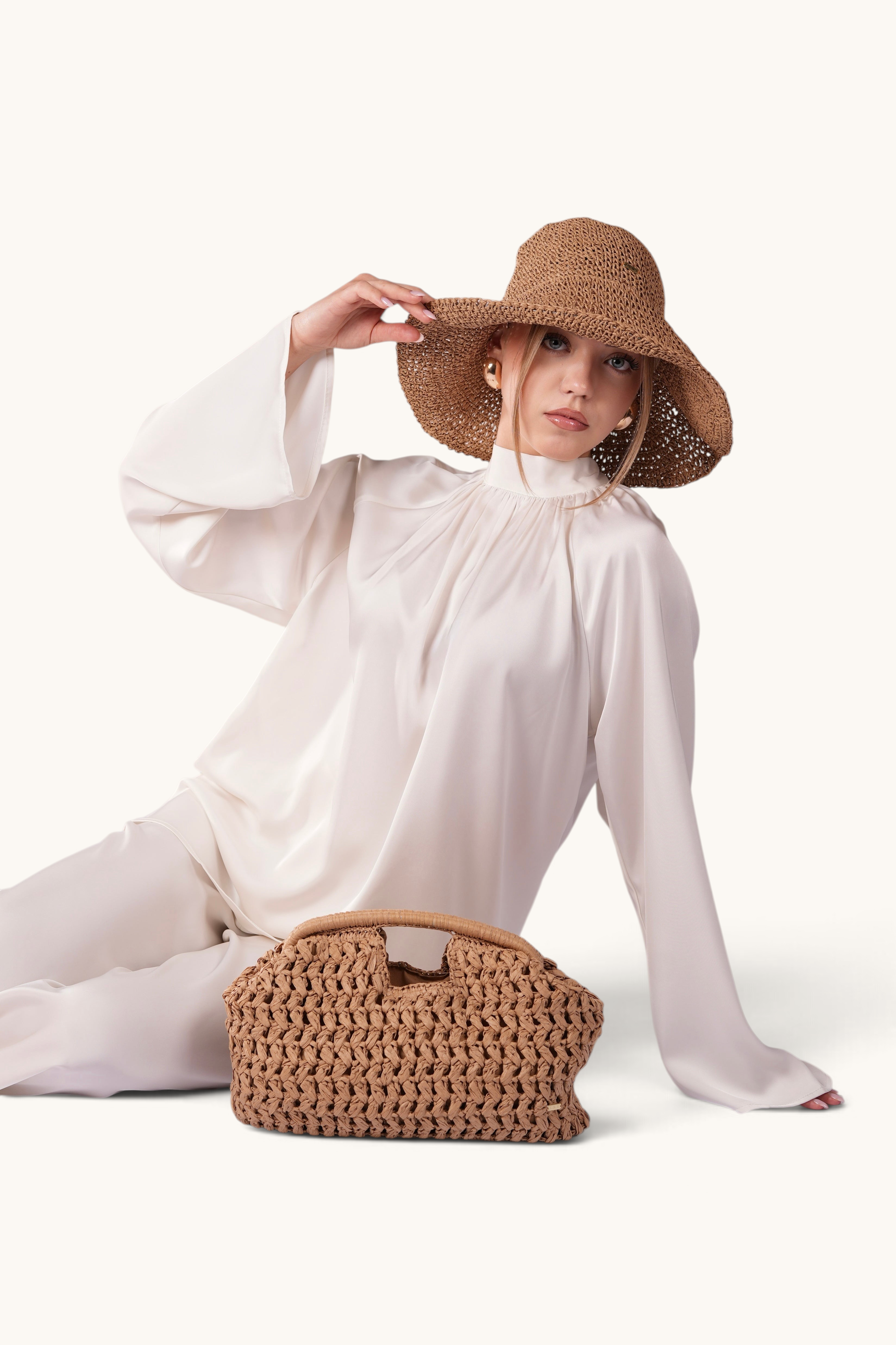 LOSYANA walnut straw hat with adjustable brim worn by a woman in a white silk outfit with a matching woven bag