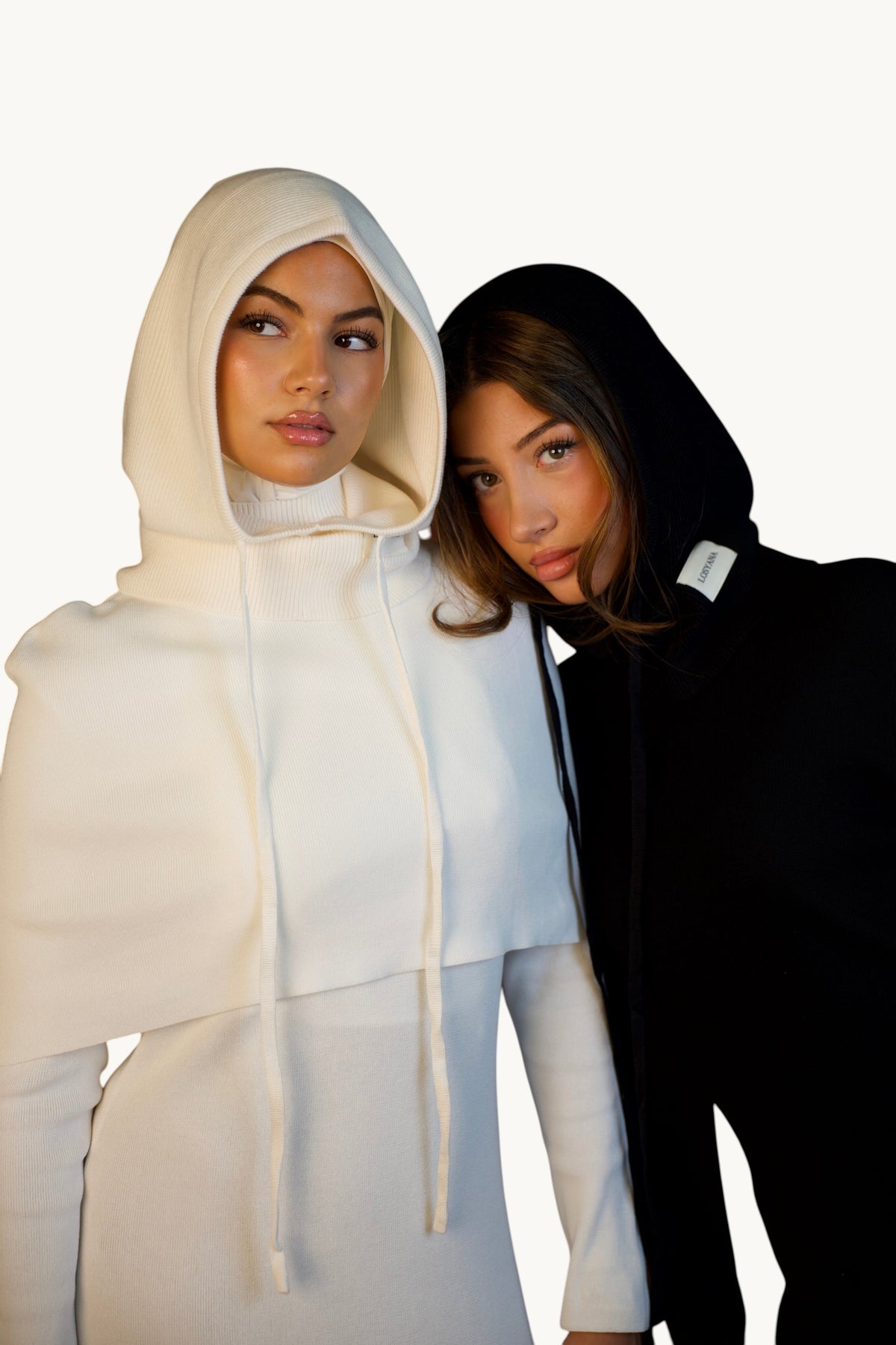 Zwei Models tragen LOSYANA Balaclava Kapuzen-Schals in Creme und Schwarz aus weichem Strick mit verstellbarem Kordelzug