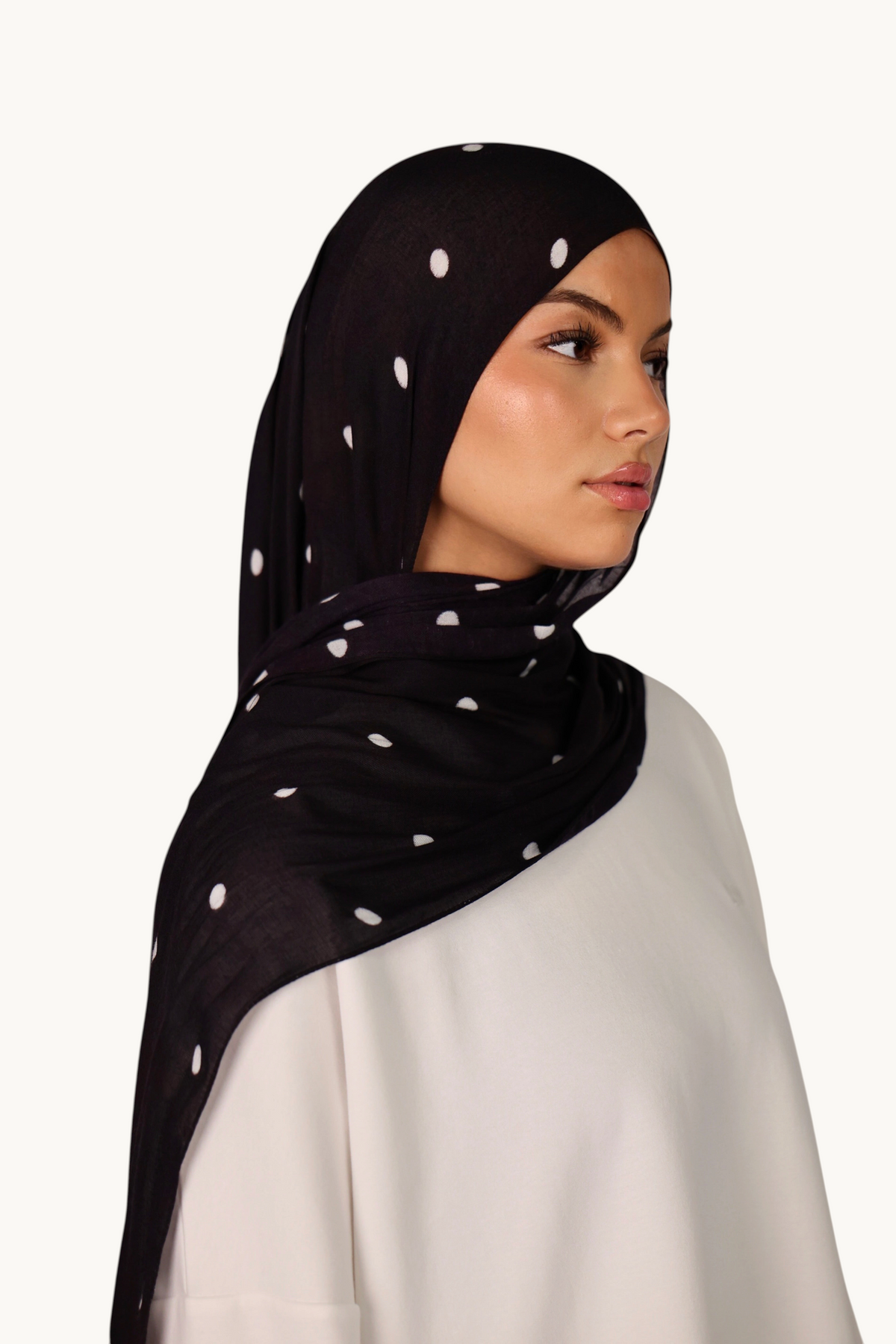 LOSYANA Hijab aus schwarzem Modal mit weißen Velour-Punkten, getragen von einem Model vor hellem Hintergrund