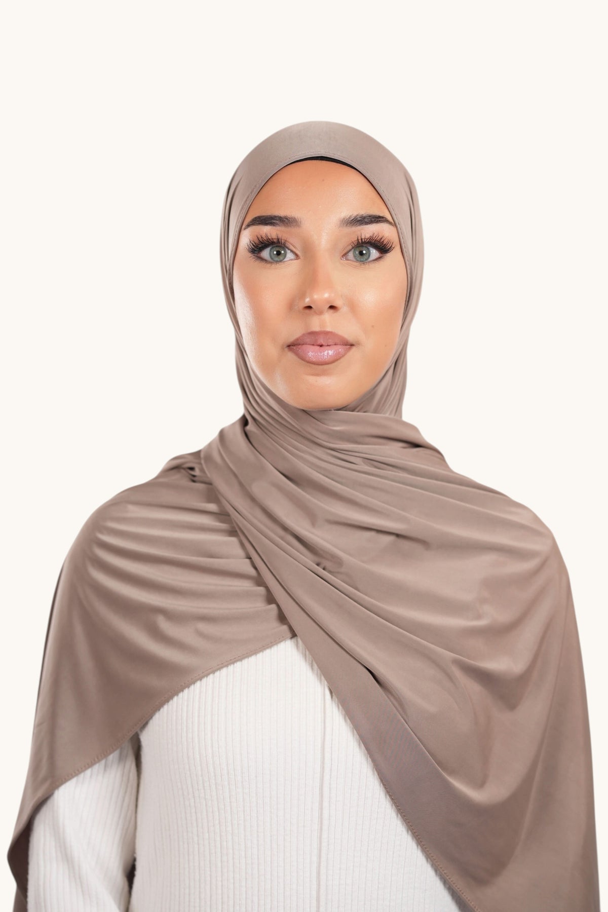 Hintergrundbild eines dunkel beigen Liquid Jersey Hijabs von Losyana.Shop, fließend und weich, trägt elegant um den Hals.