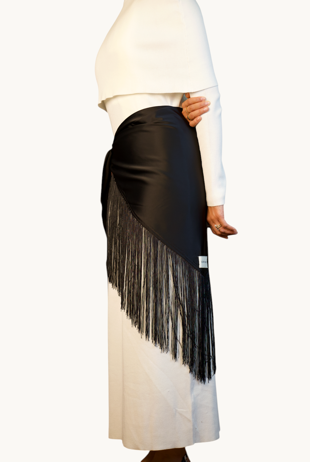 LOSYANA schwarzes Satin-Cape mit langen Fransen, getragen als eleganter Rock über einem weißen Kleid