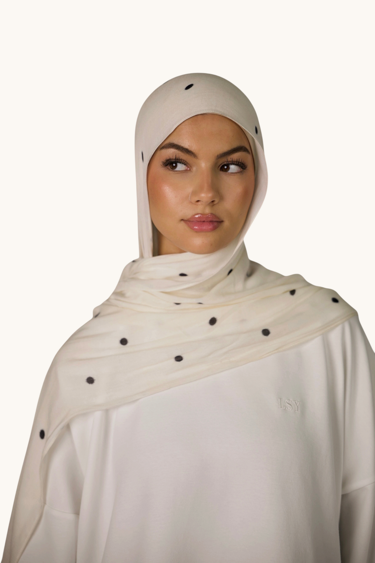LOSYANA leichter Modal Hijab in Creme mit schwarzen Velour-Punkten, getragen von einem Model mit passender Bone.