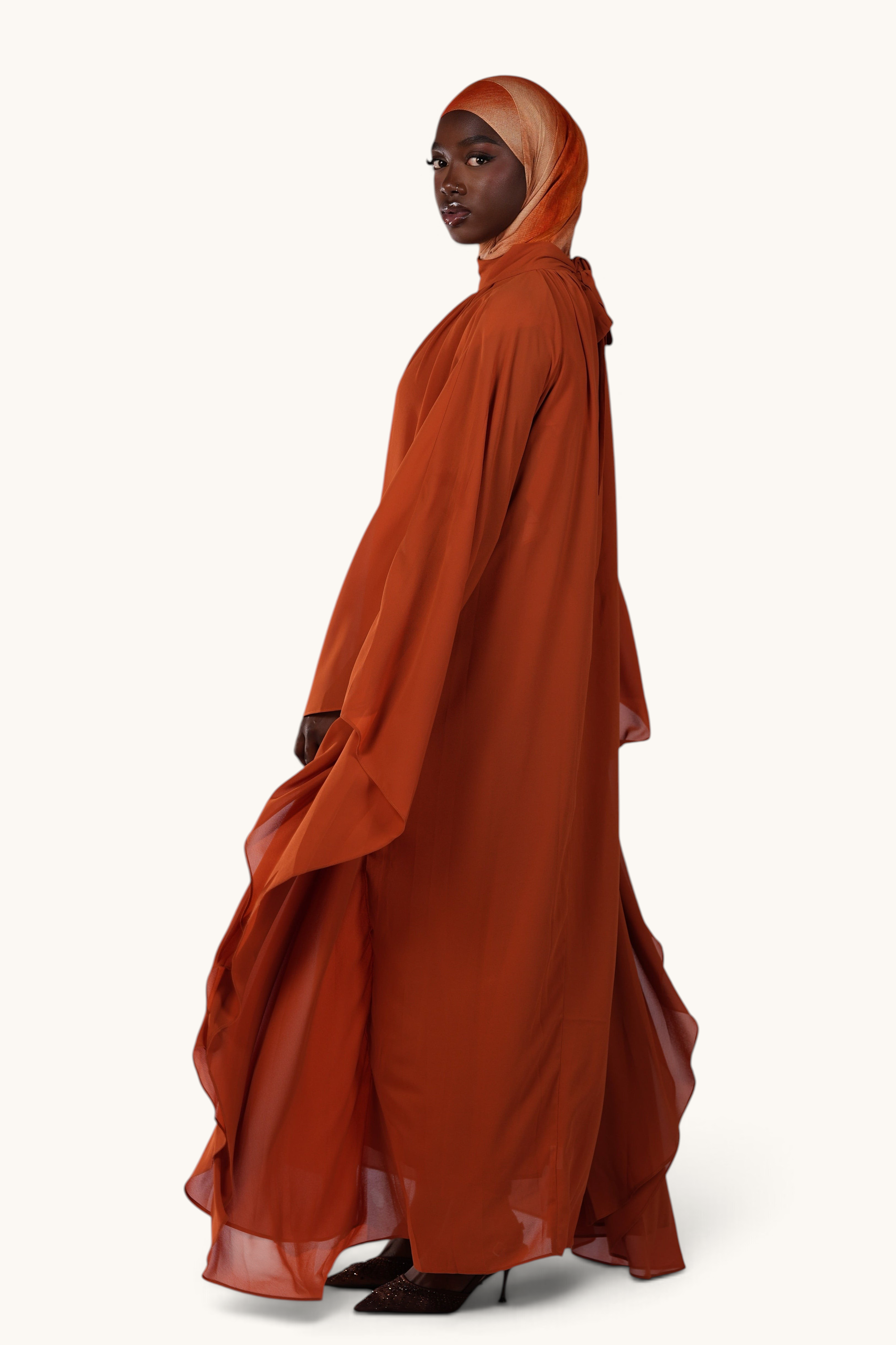 LOSYANA Andalusia sunset orange chiffon cape dress worn by a model with a matching hijab, side profile view