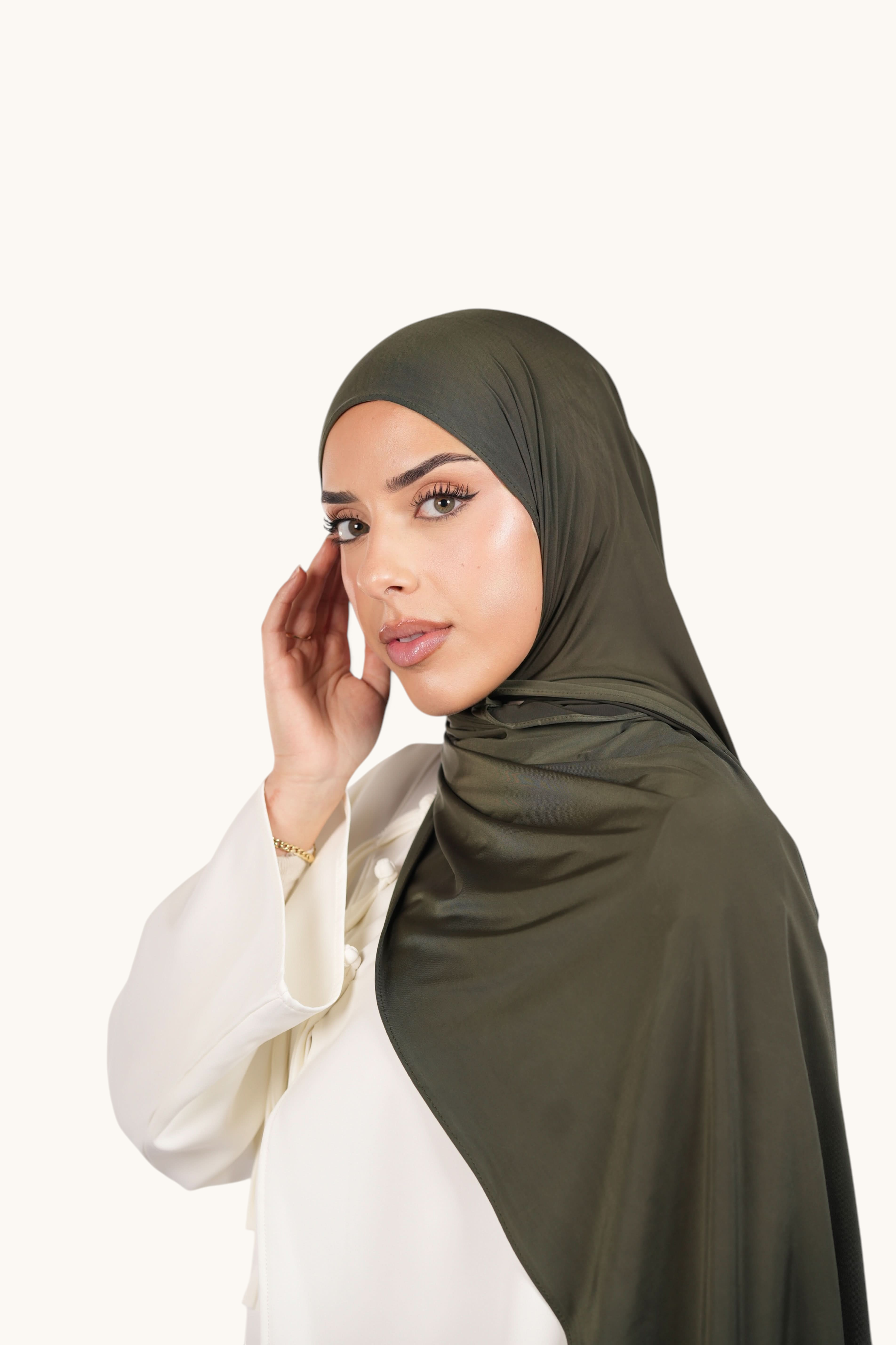 Model wearing a LOSYANA army green Liquid Jersey hijab with a subtle satin sheen, styled over a white top.
