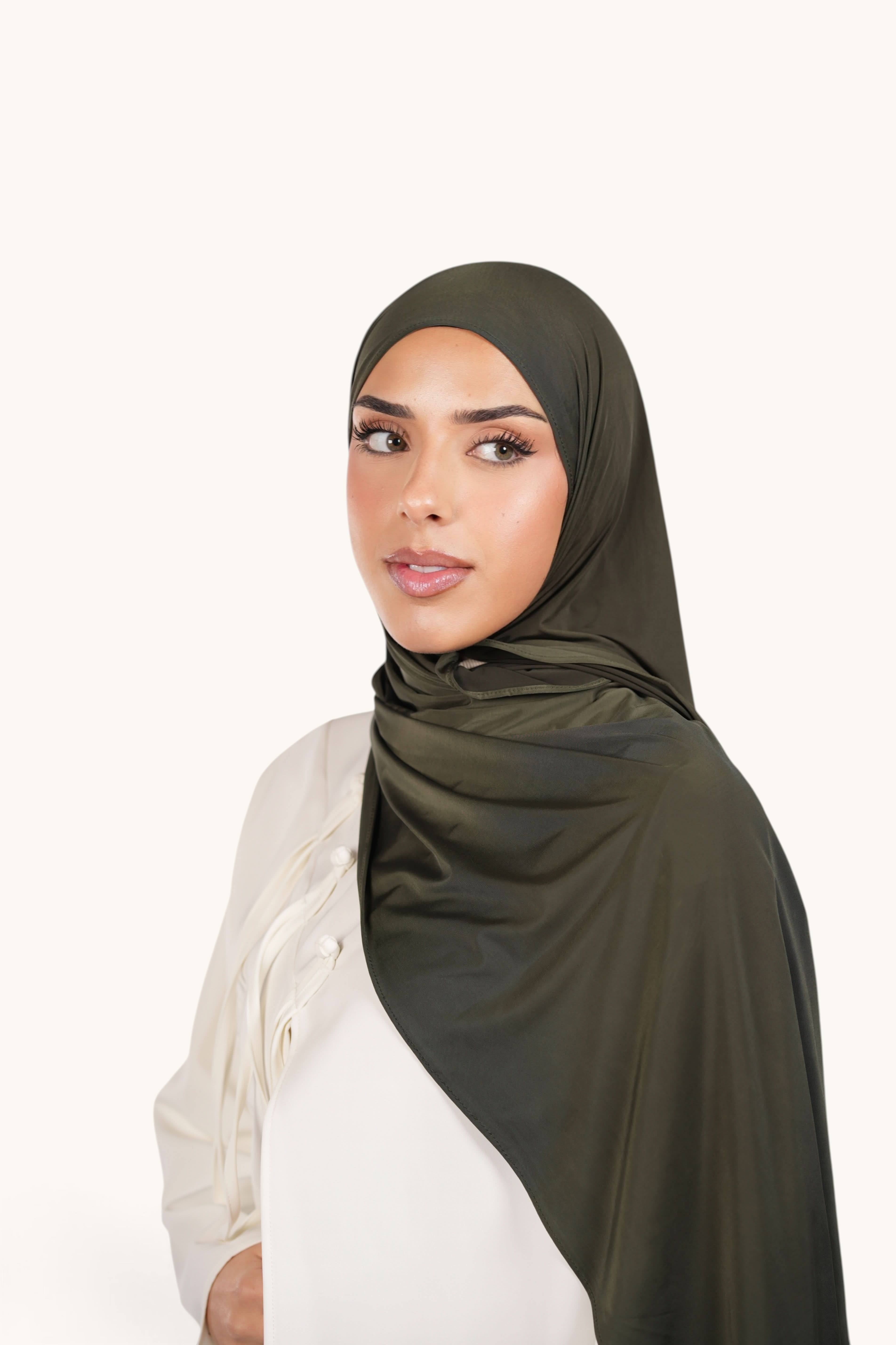 Model wearing a LOSYANA army green liquid jersey hijab with a subtle satin sheen, styled elegantly.