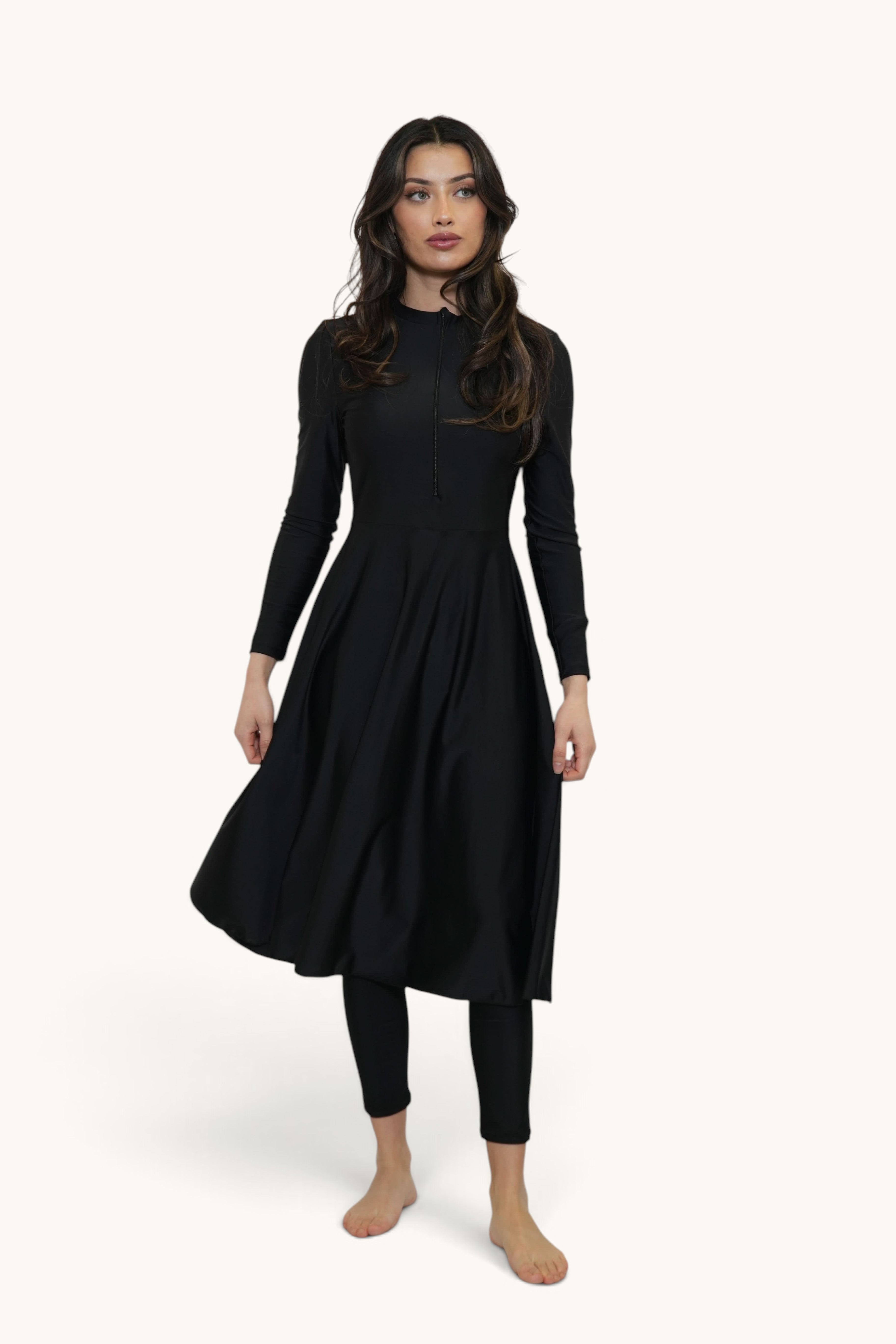 Model wearing a LOSYANA Azzurra black long-sleeve burkini set with a knee-length tunic and matching leggings