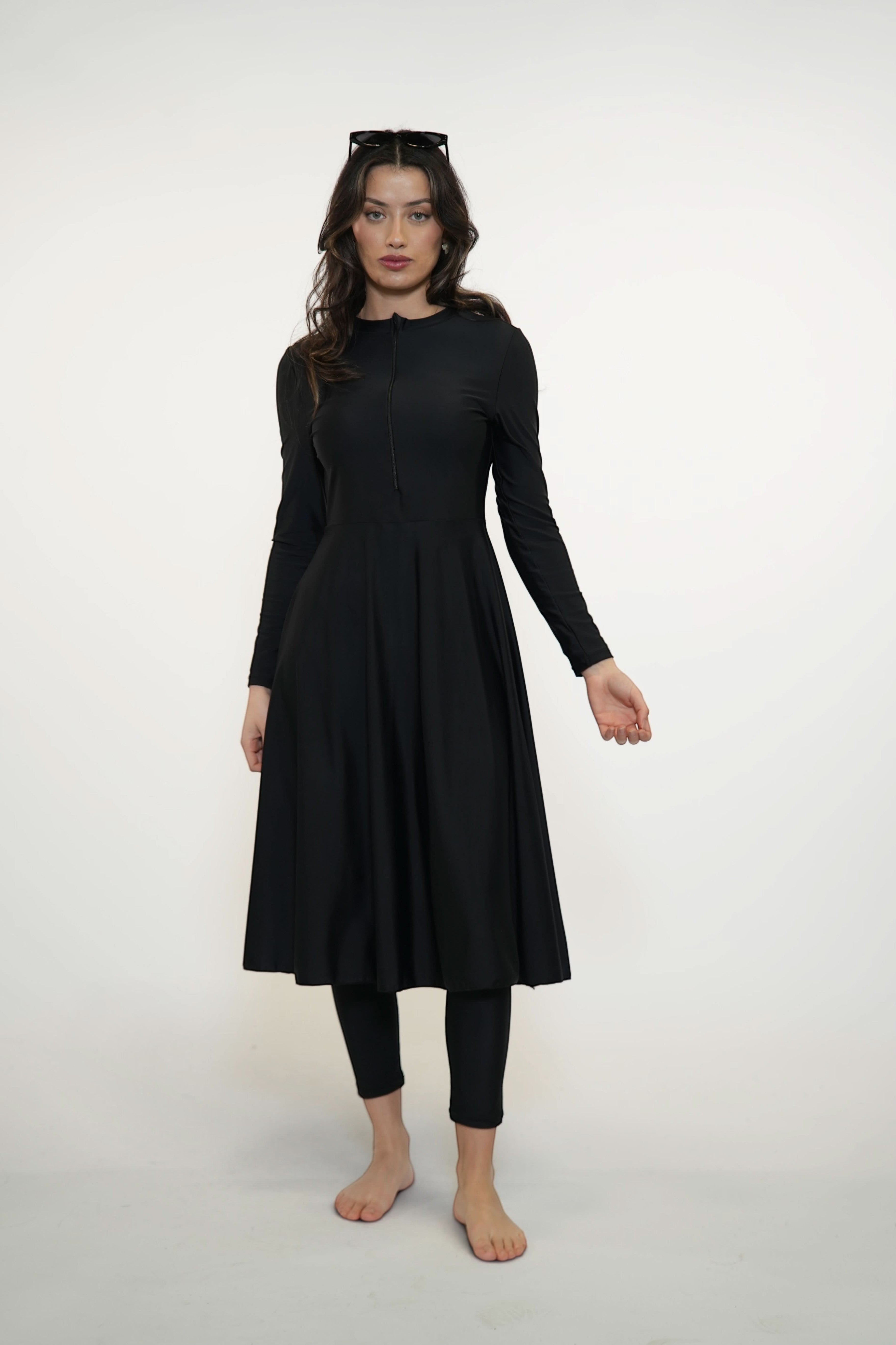 Model wearing a black LOSYANA Azzurra long-sleeve burkini set with a flared tunic and leggings for full coverage.