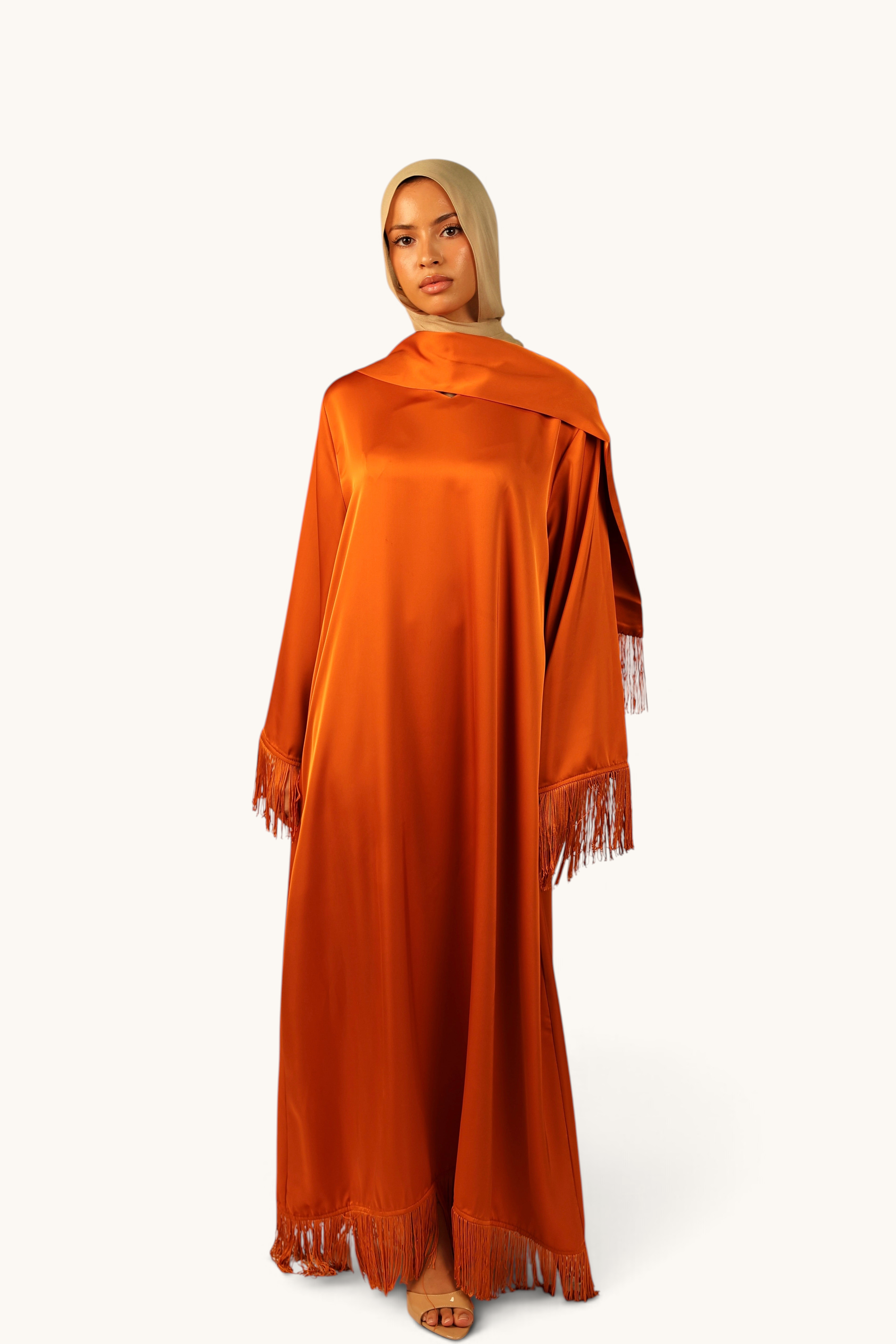 LOSYANA Barcelona Satin Kleid in Papaya mit Fransen an Ärmeln und Saum, getragen mit passendem Schal und Hijab.