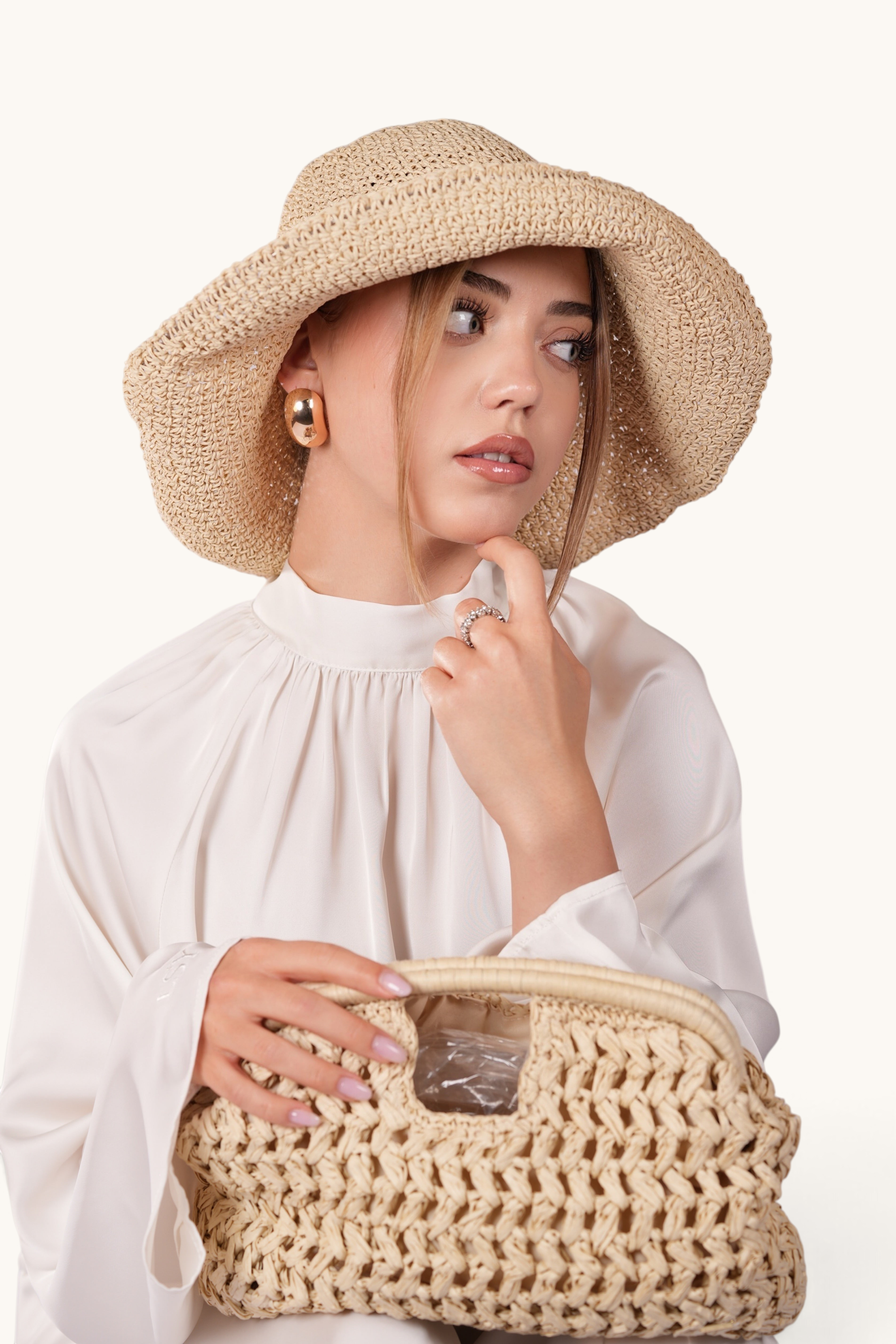 LOSYANA beige handmade straw hat with adjustable brim worn by a woman in a white blouse holding a woven bag
