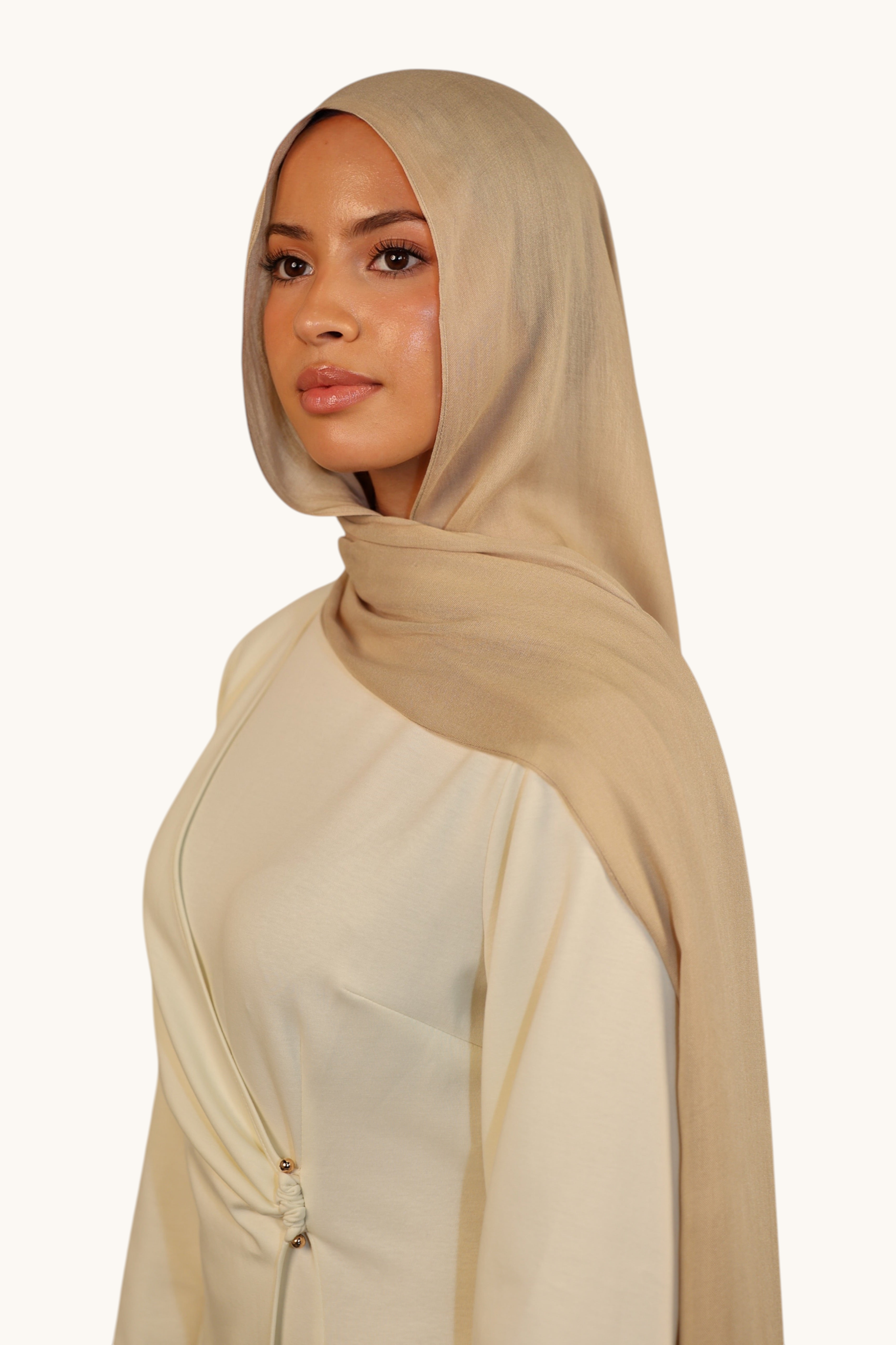 Model wearing a lightweight beige LOSYANA modal hijab with a soft, elegant drape and subtle transparency.