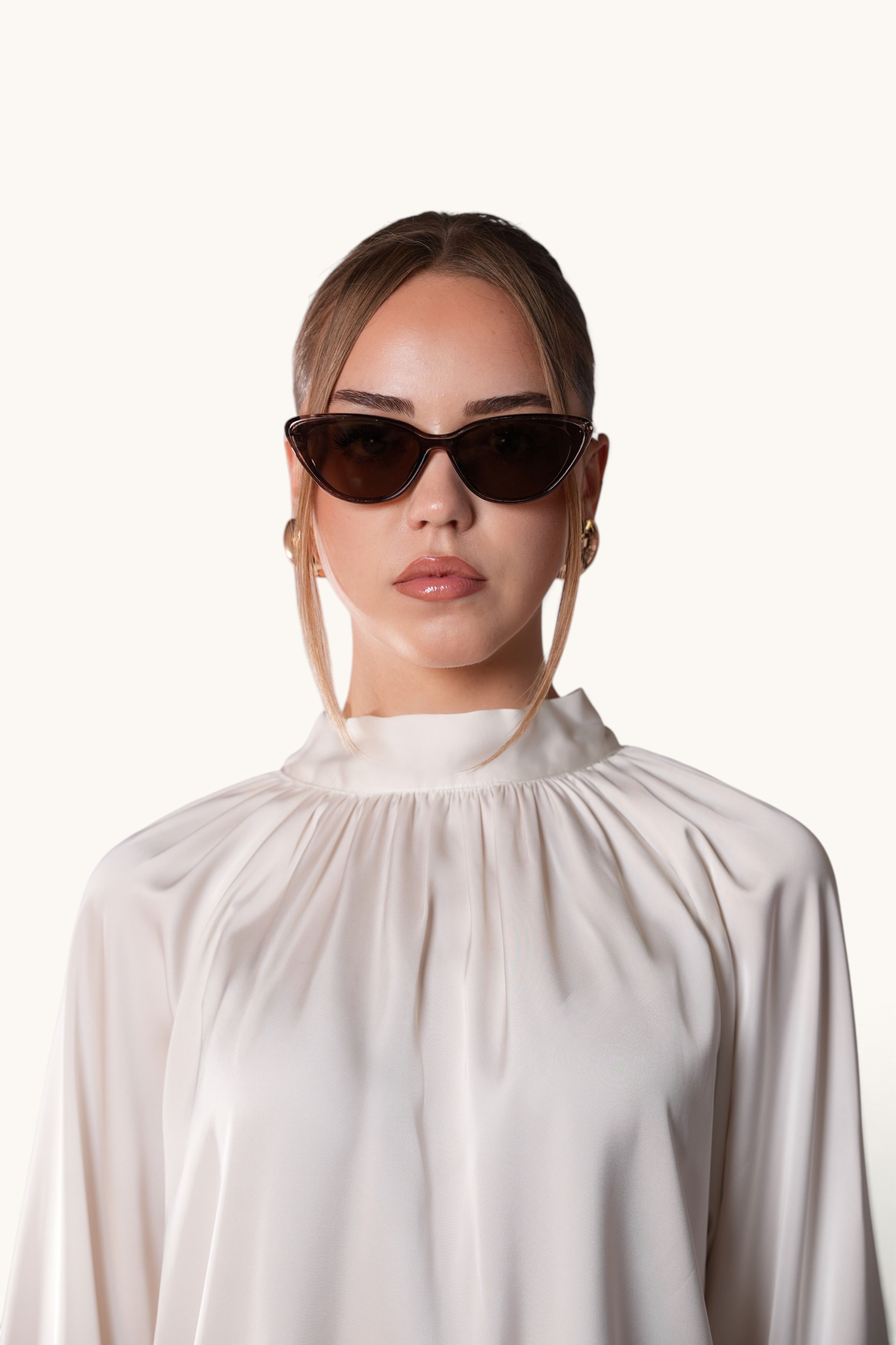 Woman wearing LOSYANA brown cat-eye sunglasses with UVA and UVB protection against a plain background