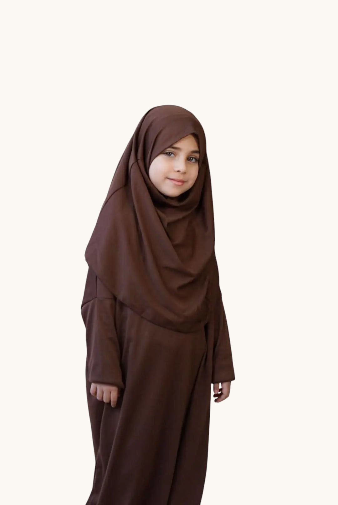 Young girl wearing a soft brown LOSYANA jersey prayer dress with an integrated hijab for comfortable daily prayer.