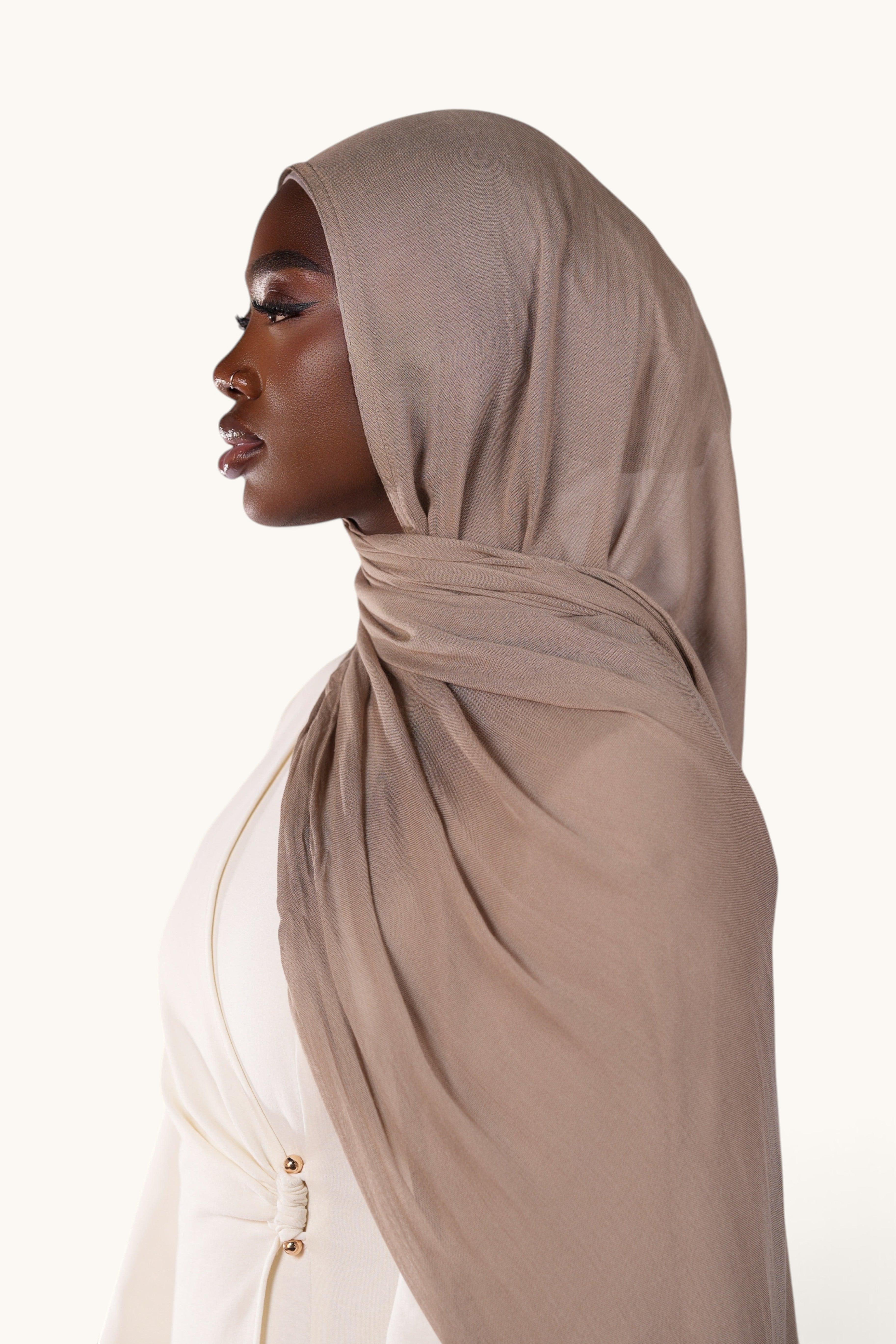 Model wearing a brown LOSYANA lightweight modal hijab with a flowing, elegant drape against a neutral background.