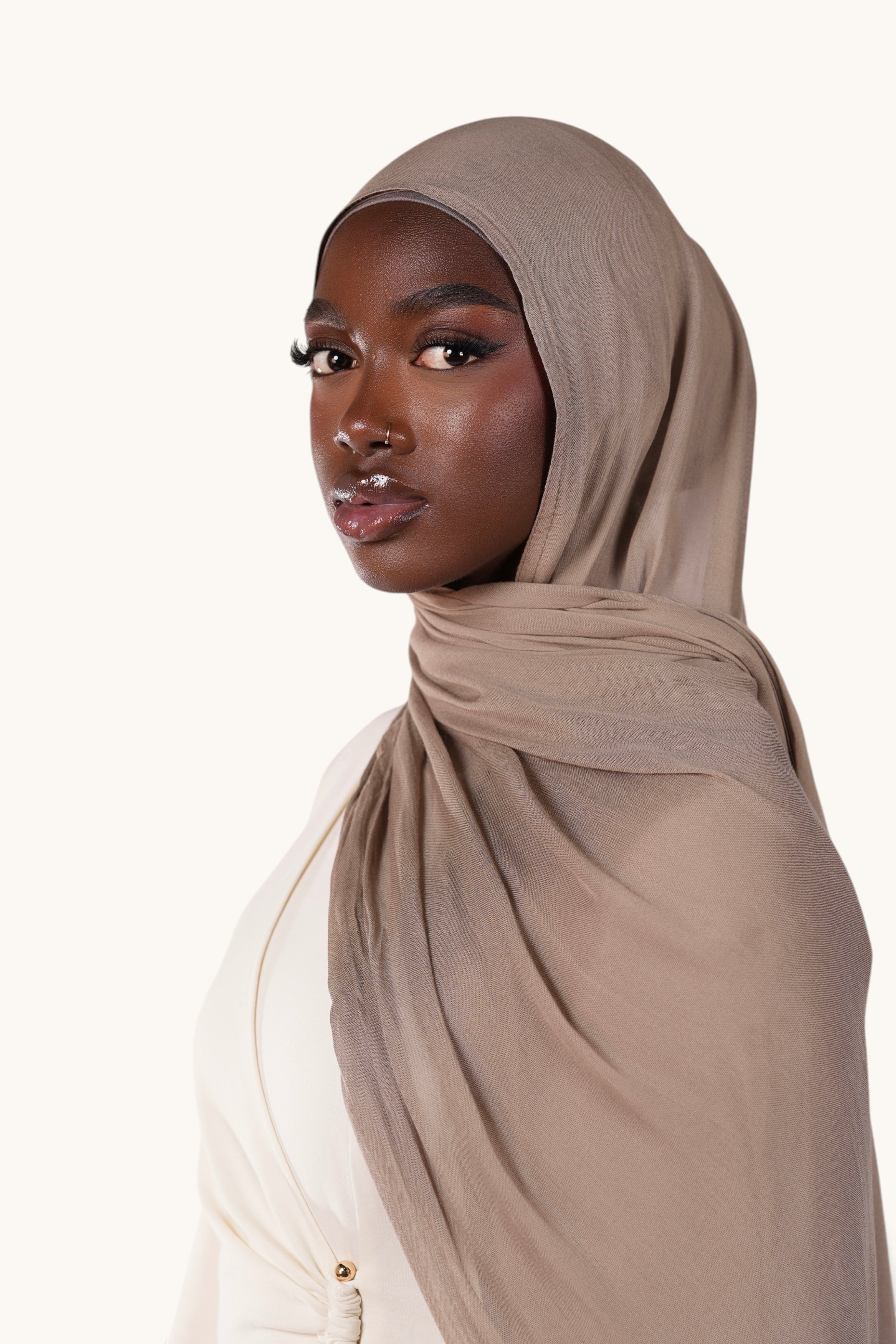 Model wearing a lightweight brown LOSYANA modal hijab with a soft, elegant drape against a neutral background.