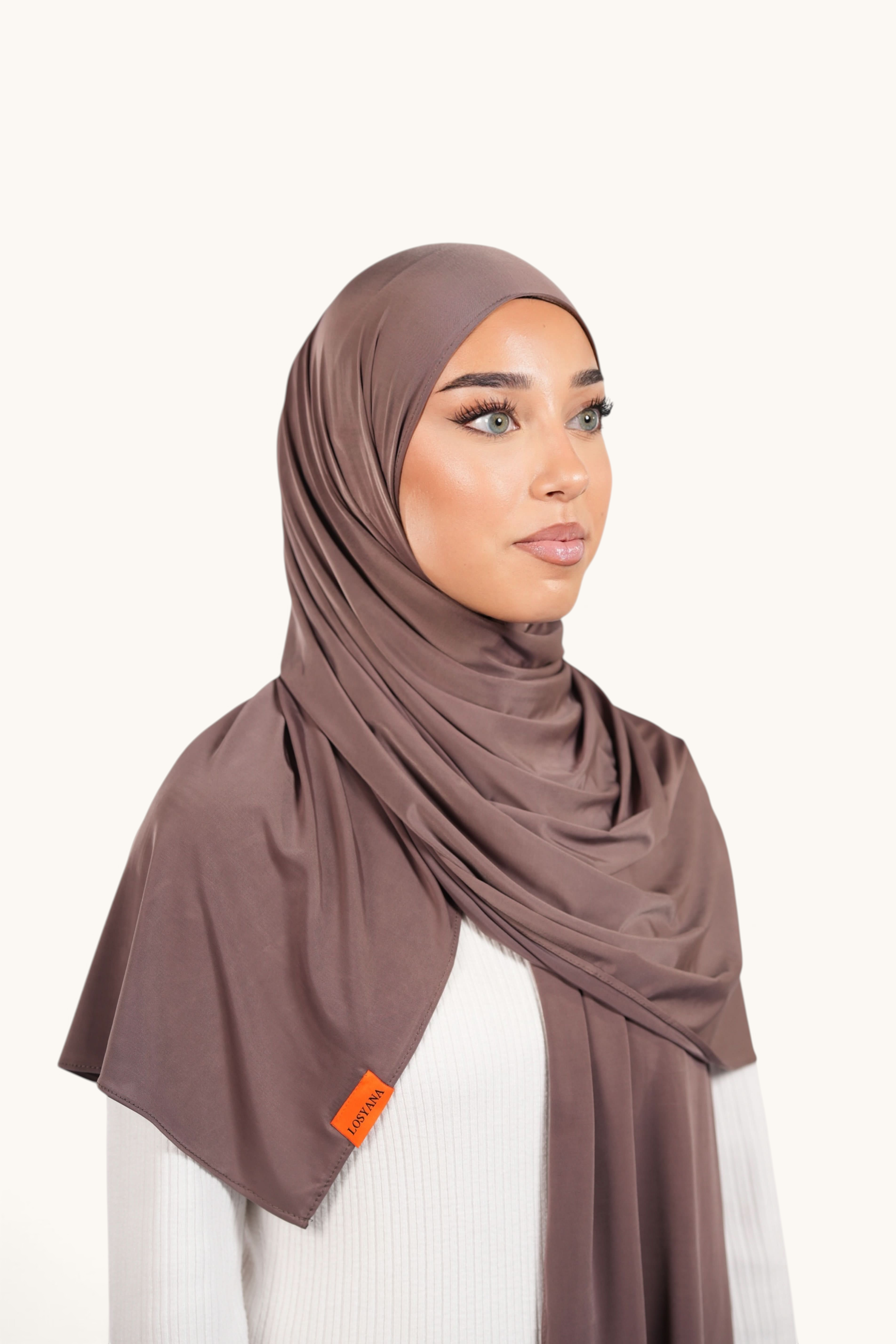 Model wearing a LOSYANA coffee brown liquid jersey hijab with a subtle sheen and branded orange tag