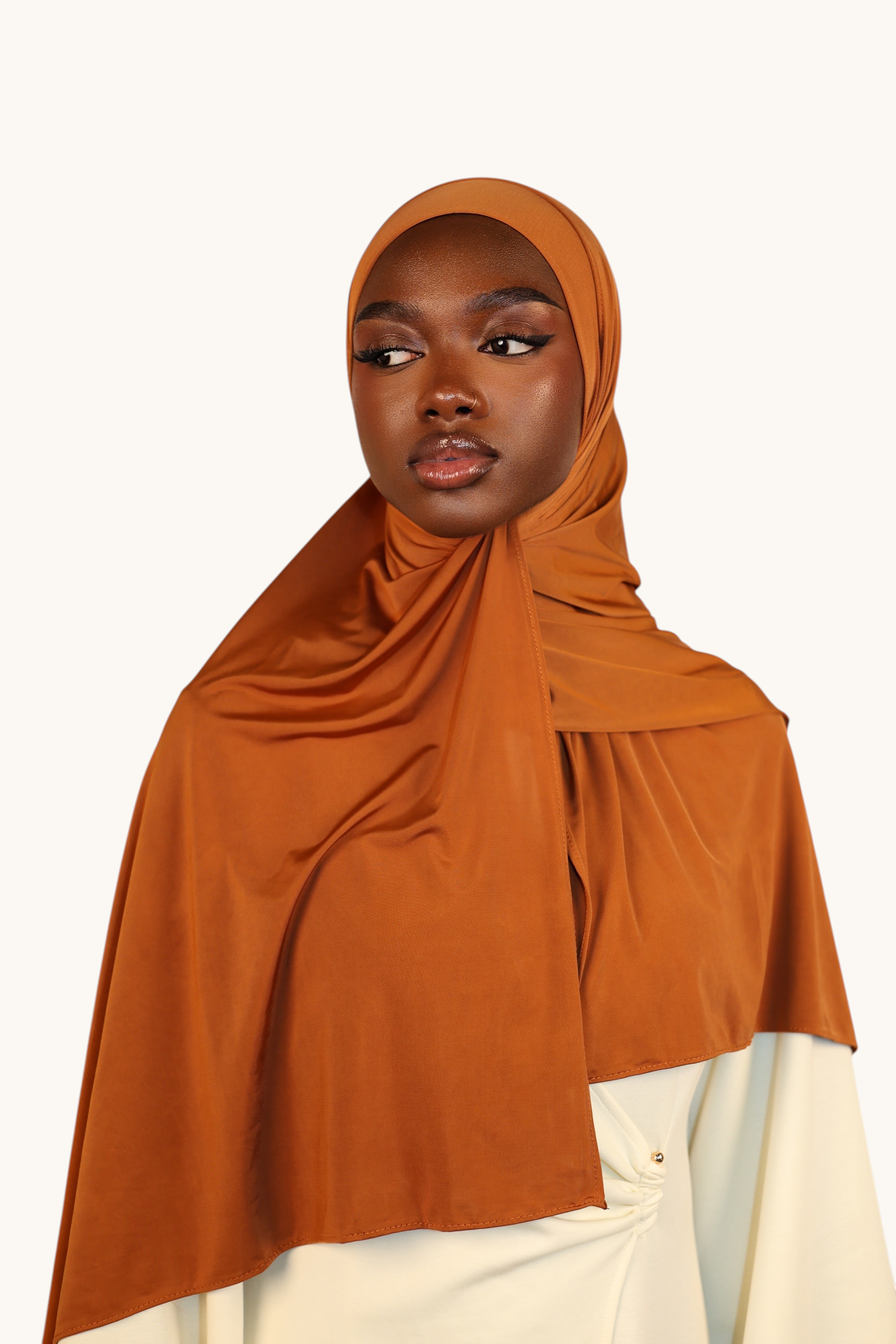 Model wearing a LOSYANA copper liquid jersey hijab with a subtle sheen, styled elegantly against a neutral background.
