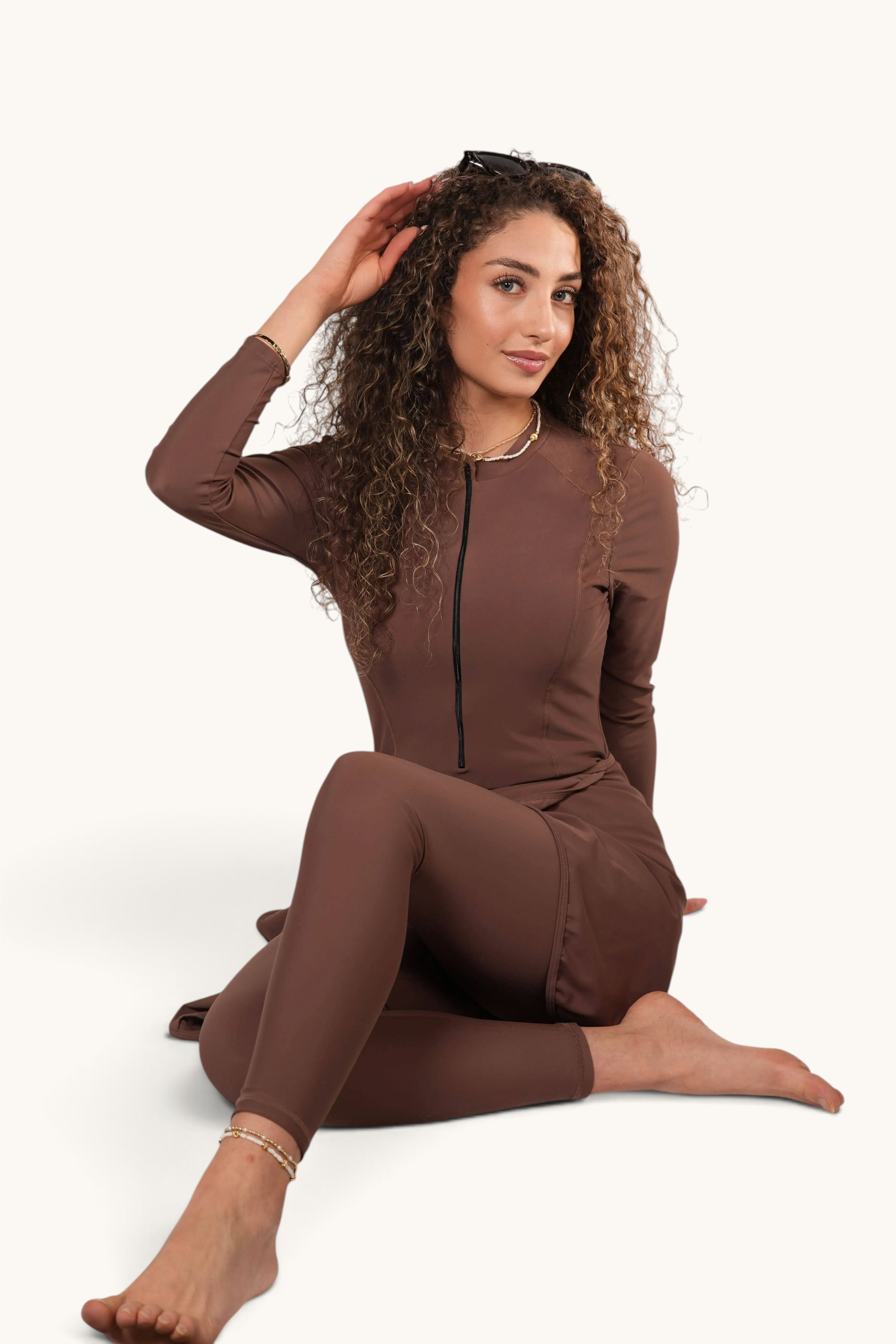 LOSYANA Costa Mare three-piece brown burkini with long sleeves, zip front, and skirt, worn by a curly-haired model.