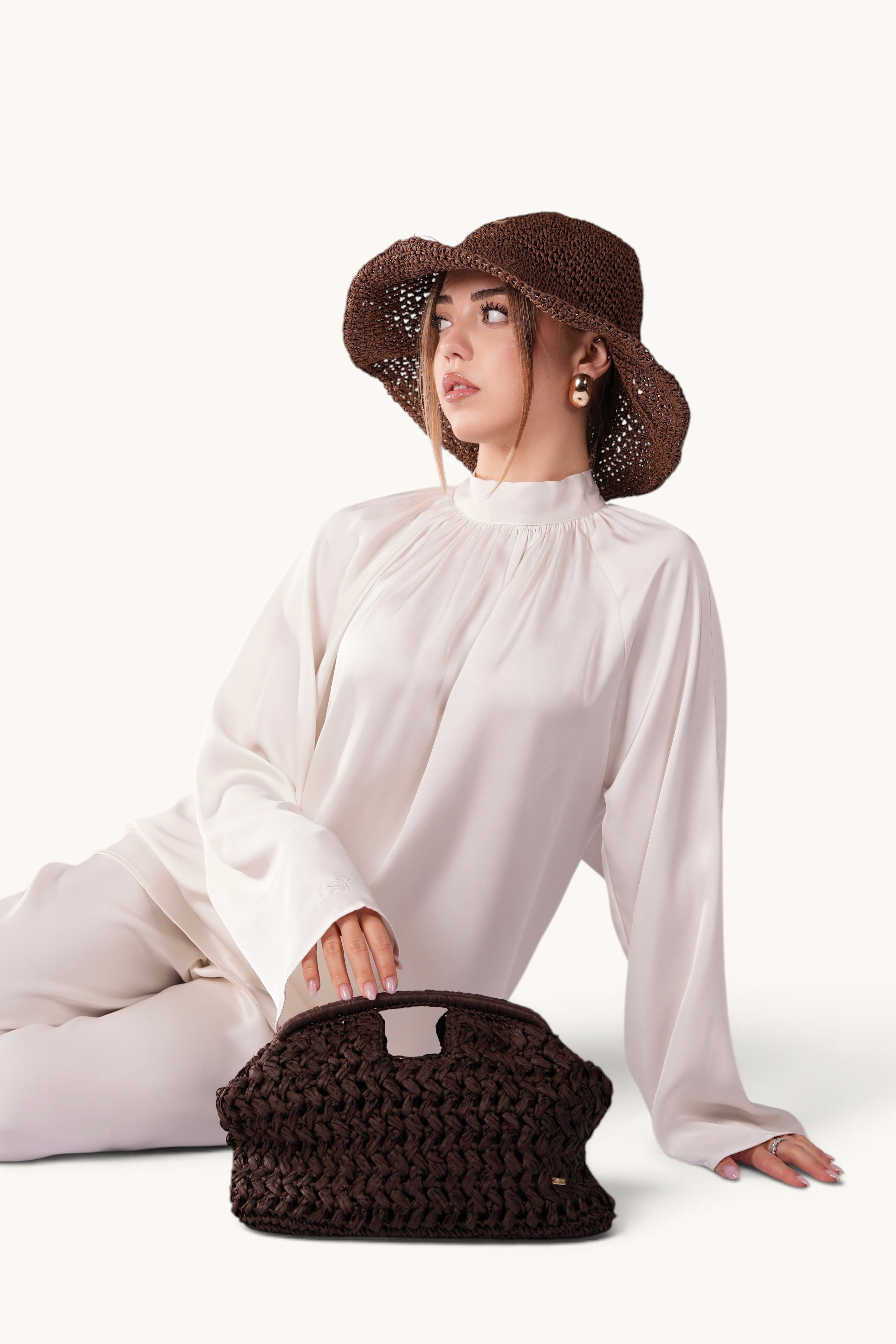 LOSYANA espresso brown handmade straw hat with adjustable brim, worn by a model in a white silk outfit.