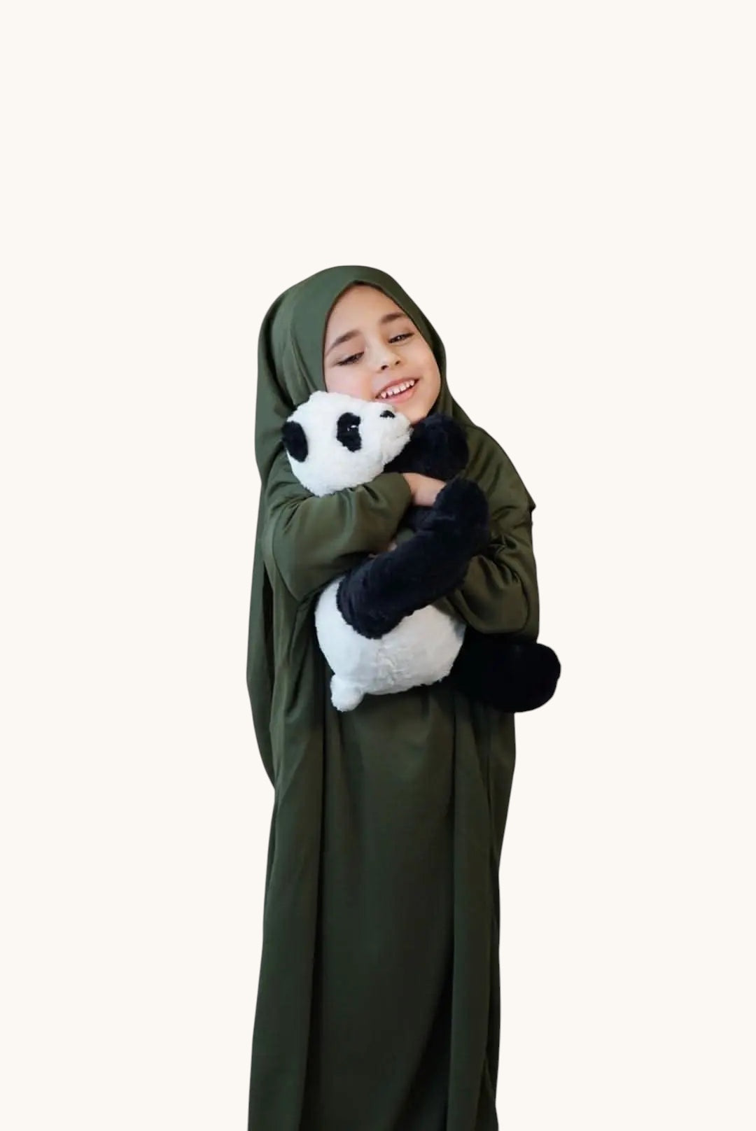A young girl wearing a khaki green LOSYANA jersey prayer dress while hugging a plush panda toy.