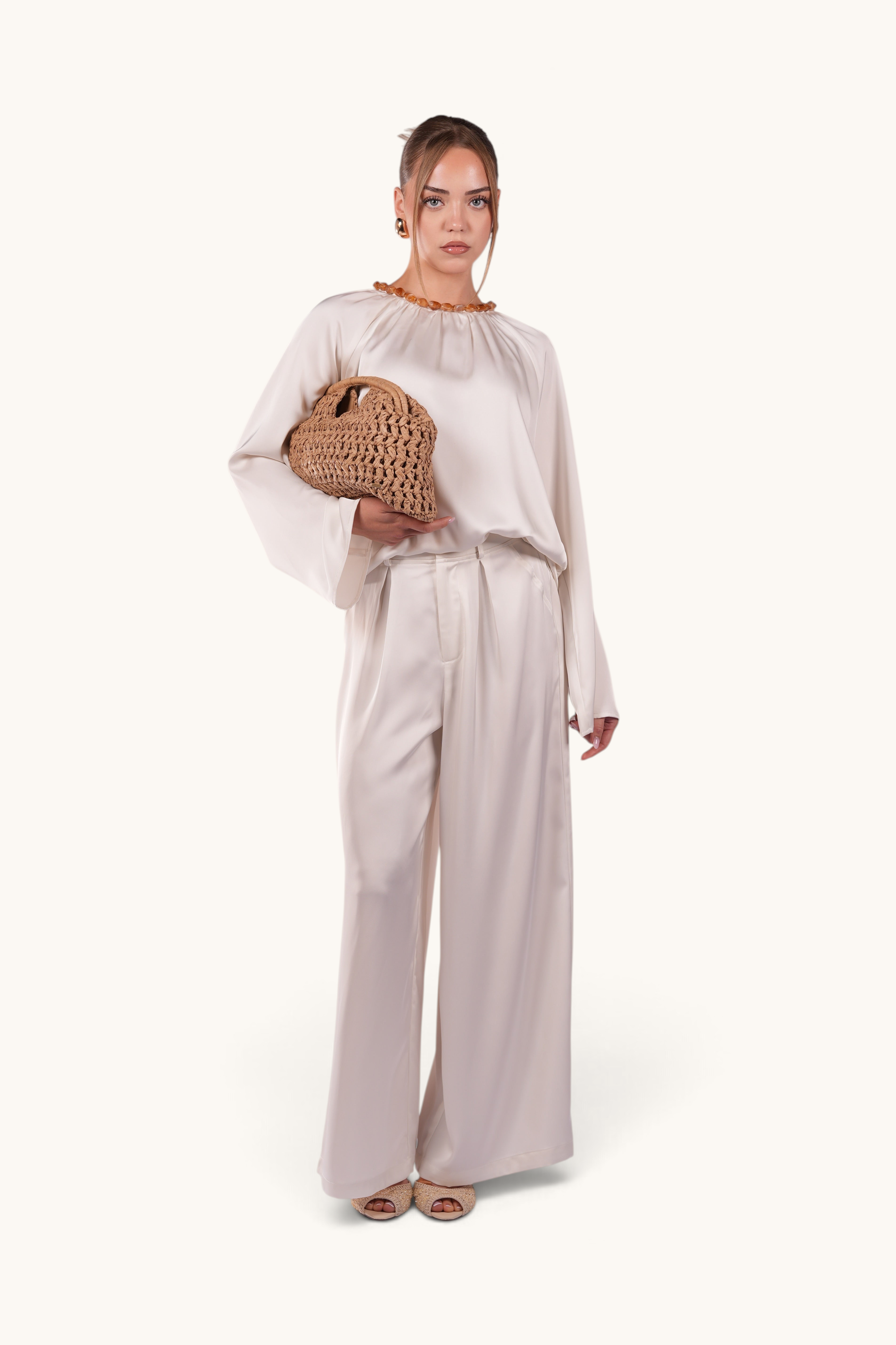 LOSYANA La Marina pearl white satin two-piece set with acrylic stone collar worn by a model holding a woven bag