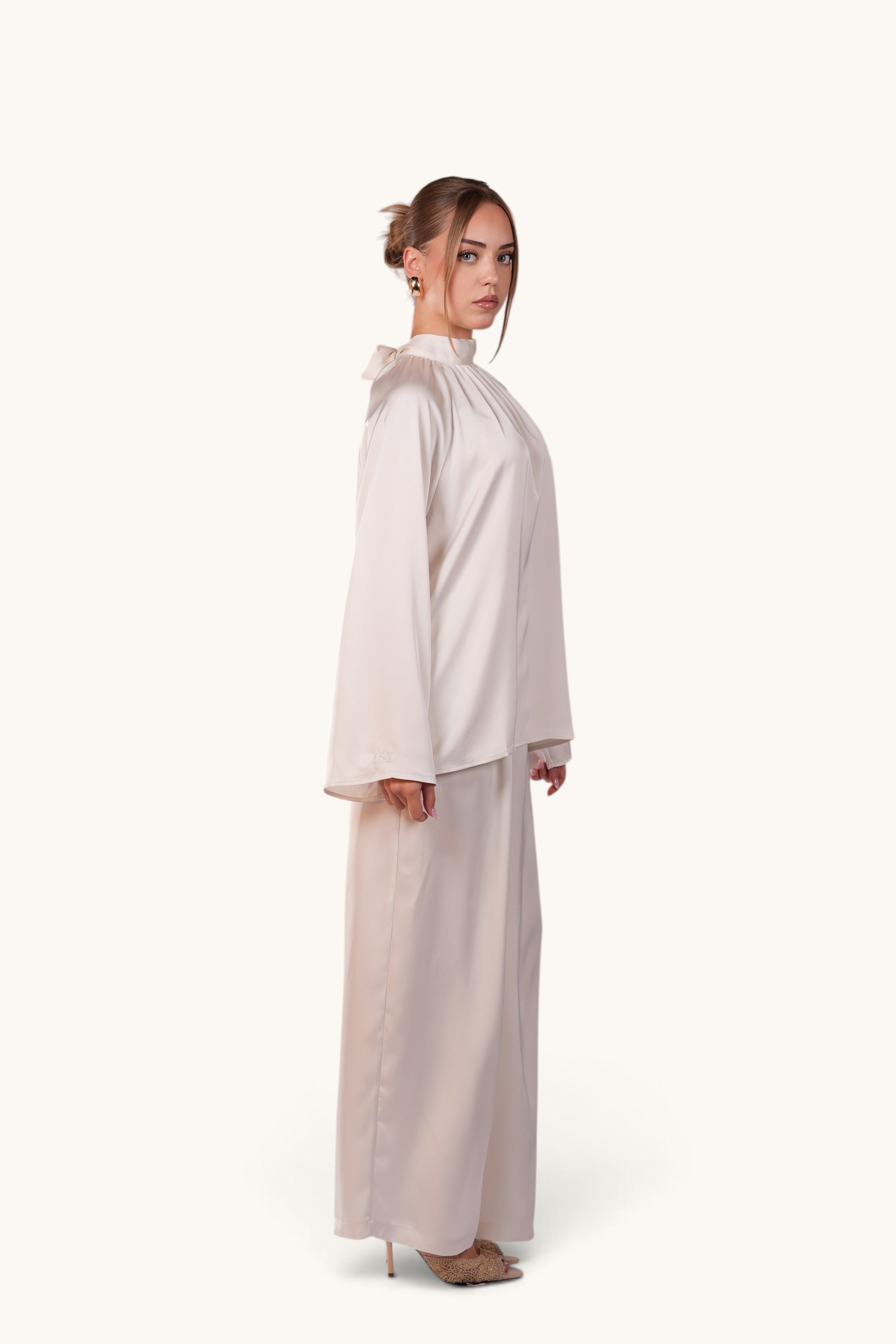 LOSYANA La Palma white satin two-piece set featuring a high-neck top with back bow and wide-leg trousers on a model.
