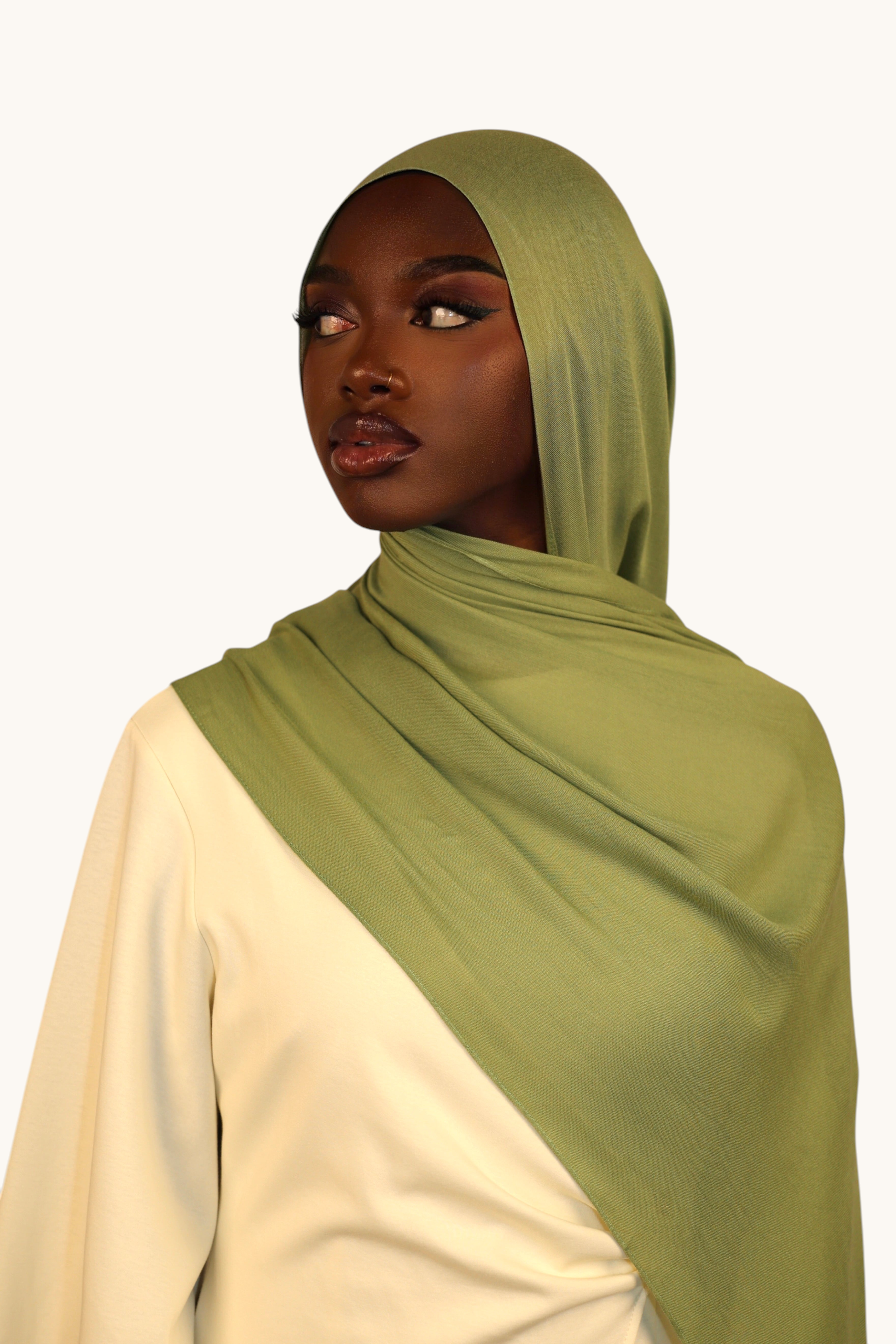 Model wearing a LOSYANA light olive green lightweight modal hijab with a matching undercap for an elegant look