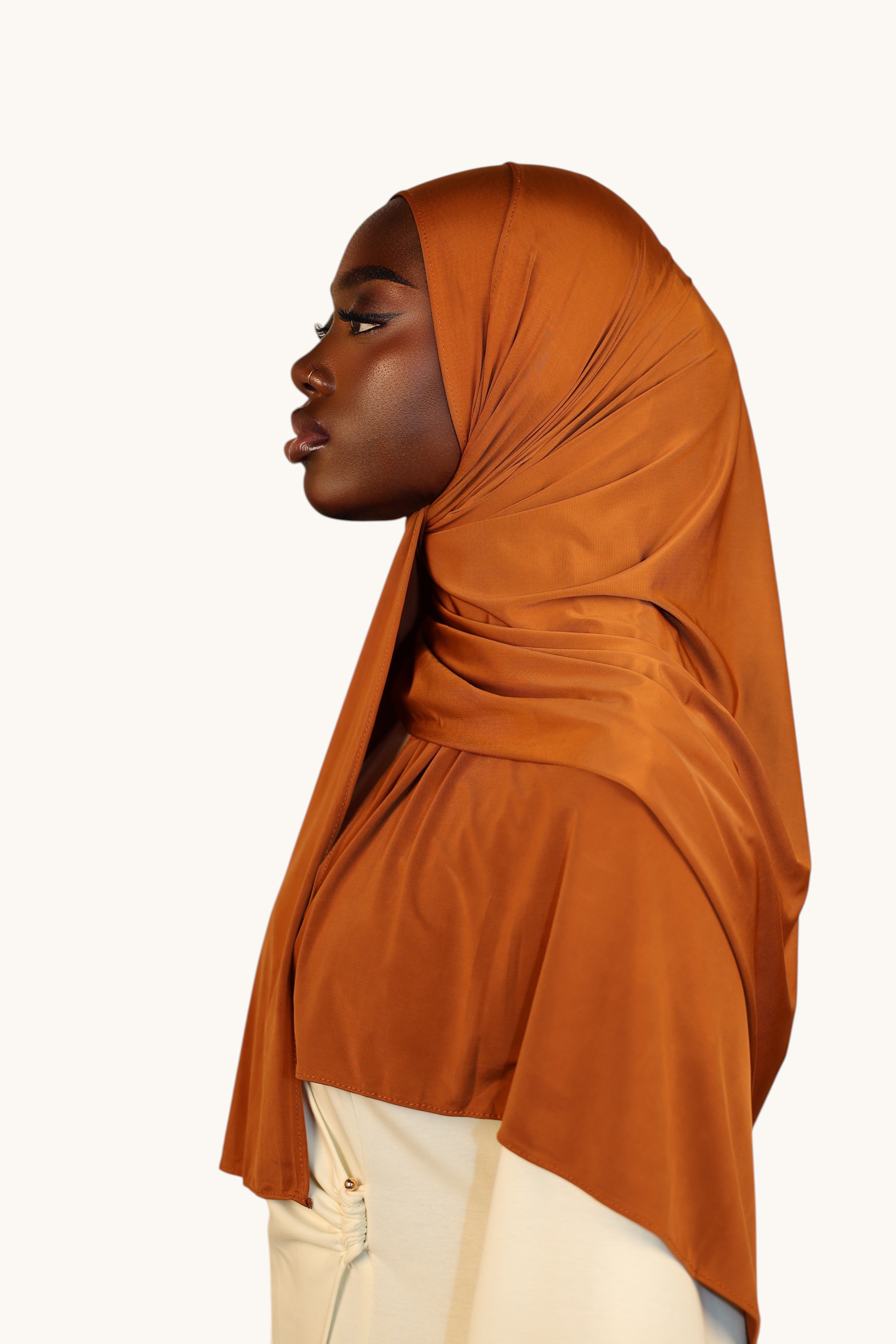 LOSYANA Liquid Jersey hijab in copper, featuring a lightweight, silky finish worn by a model in profile view.