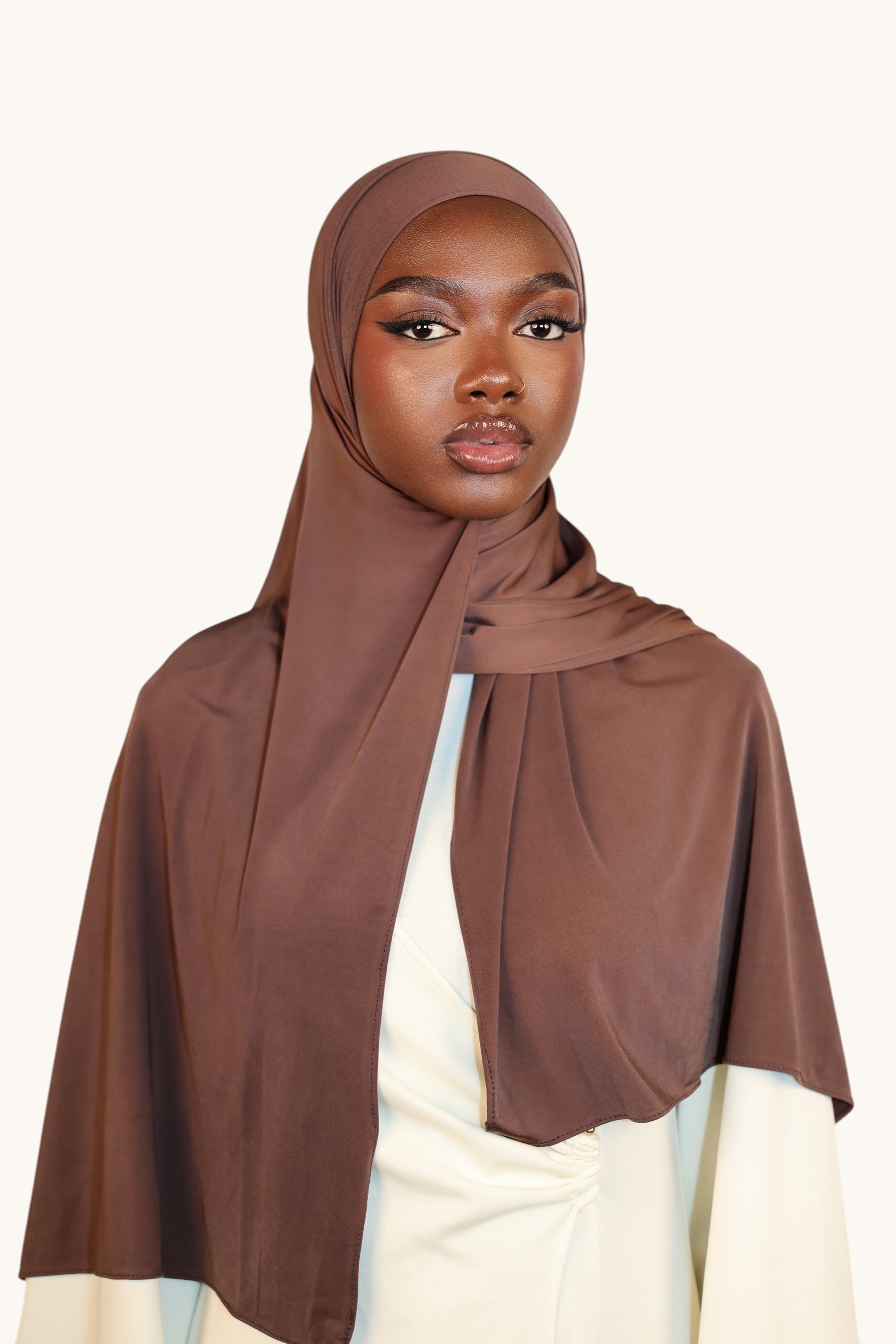 Model wearing a LOSYANA Liquid Jersey hijab in burnt sugar, a lightweight, subtly shimmering brown fabric.